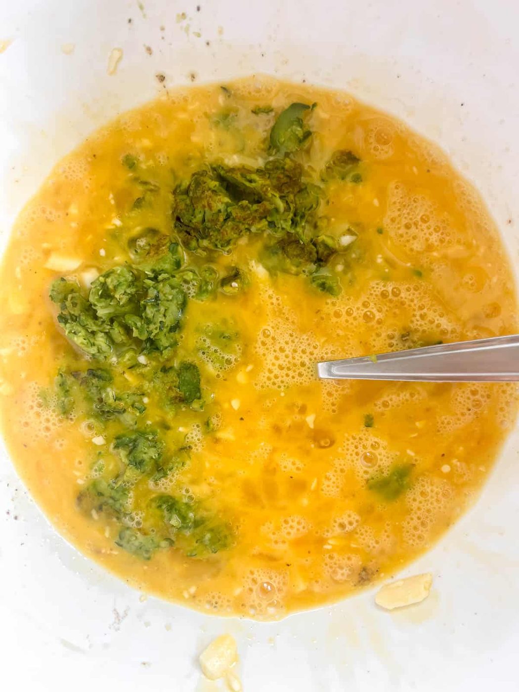Zucchini added to the eggs in a bowl.