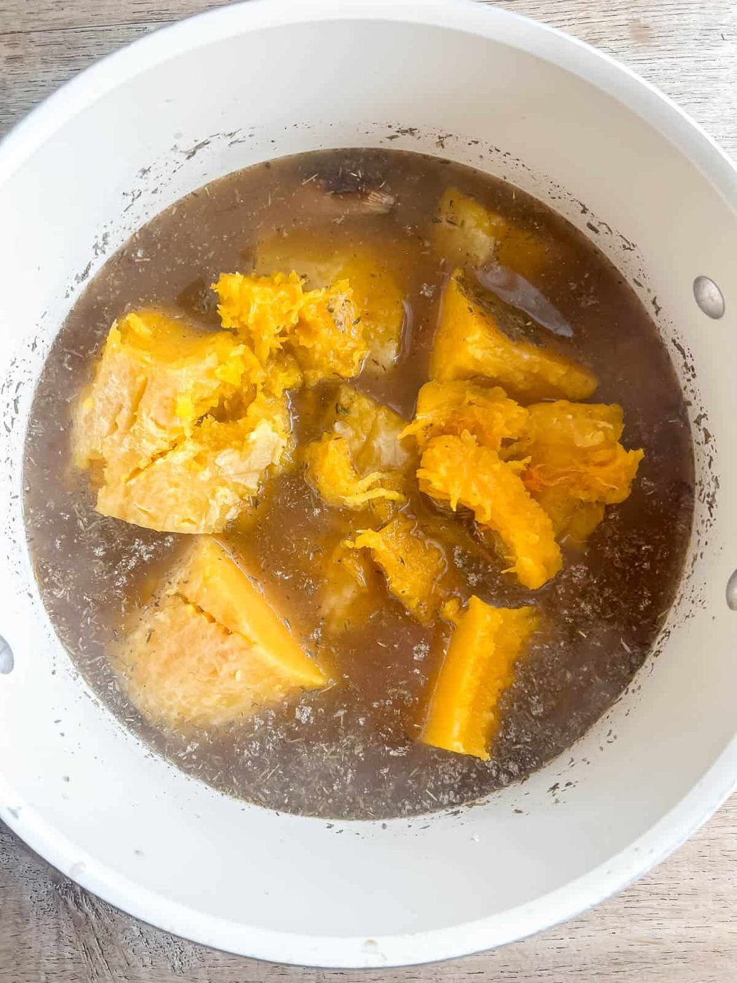 Roasted butternut squash added to a soup pan.