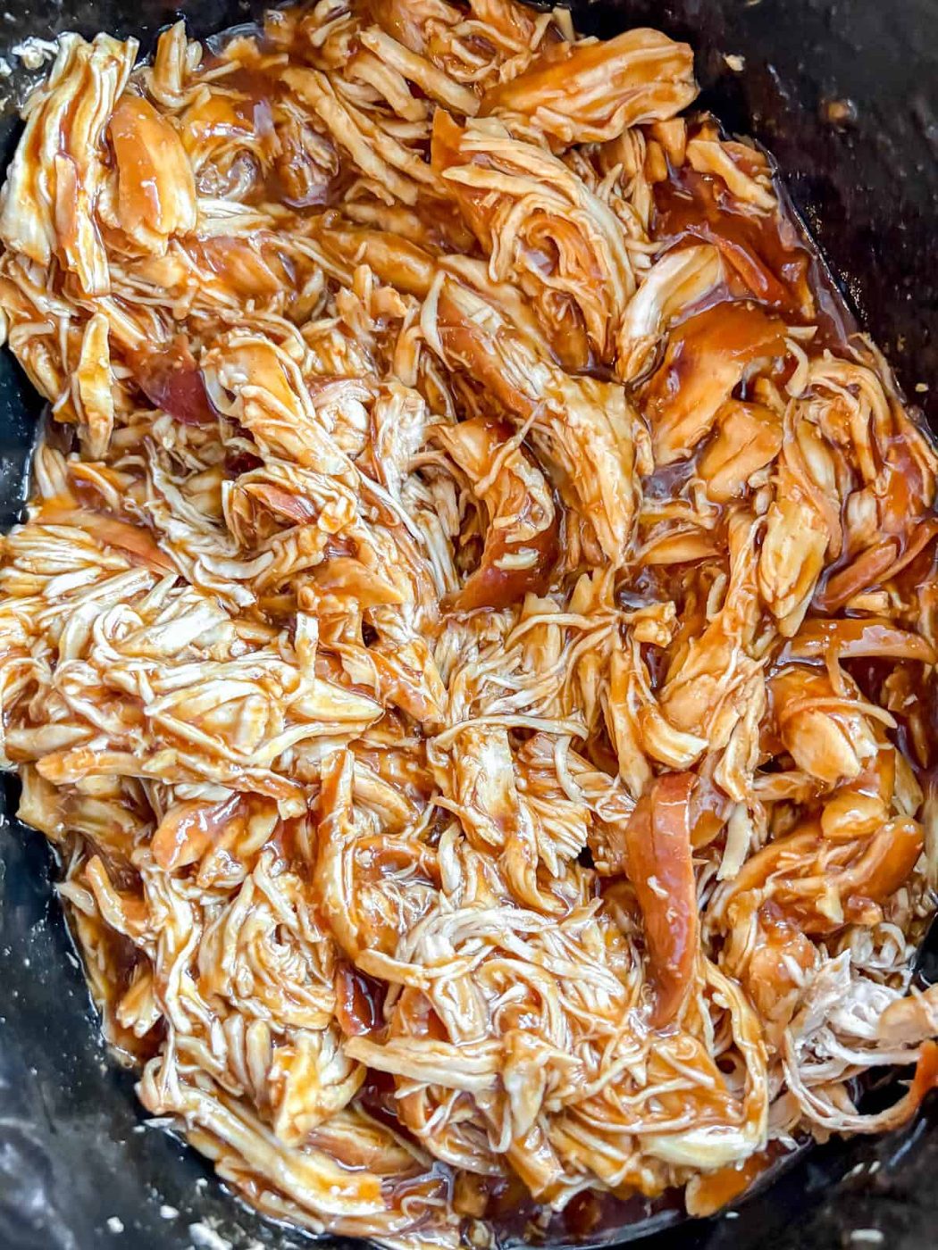 Honey garlic chicken in slow cooker after cooking and shredding.