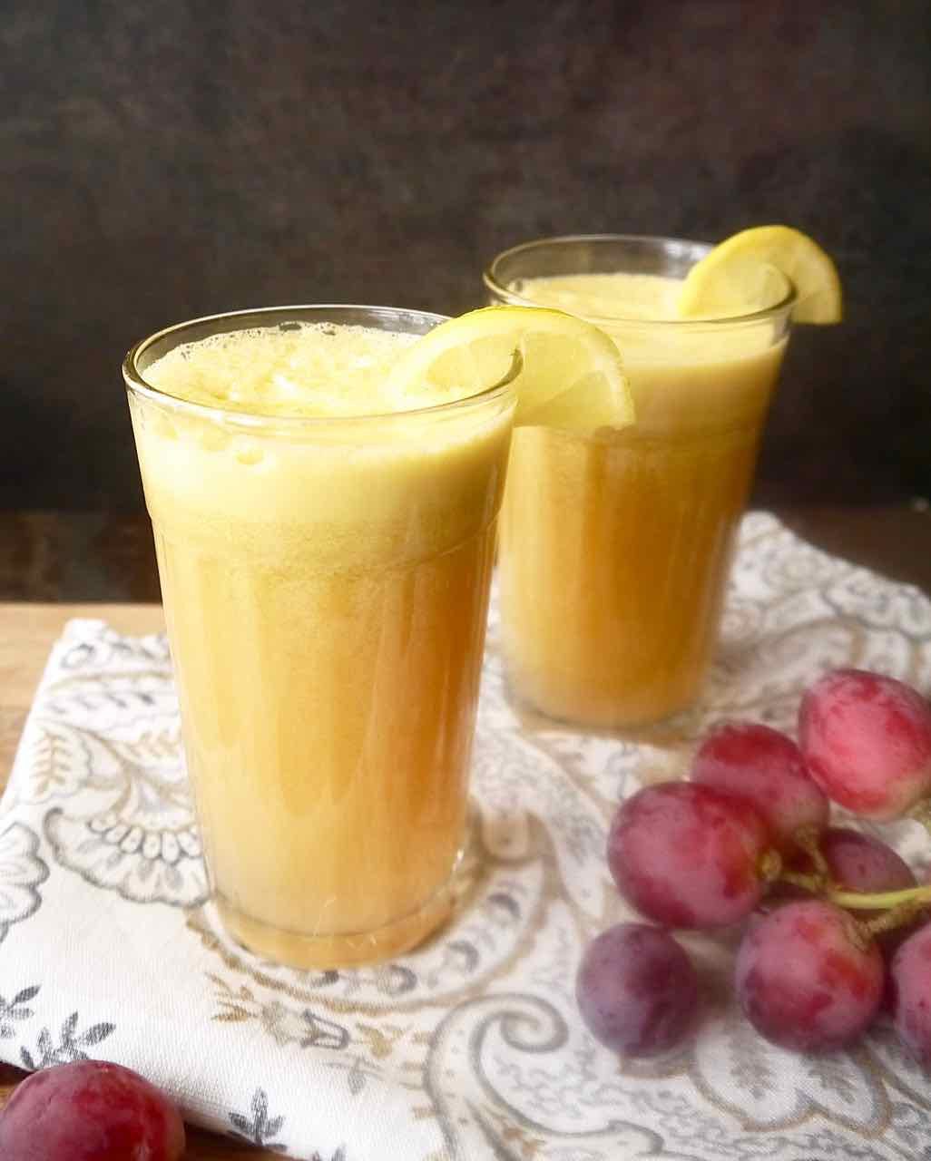 Fennel bulb juice in 2 glasses and grapes next to them.