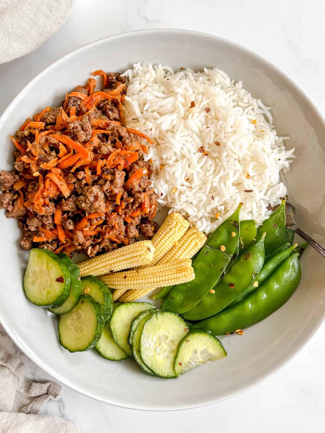 Korean ground beef bowl with rice, snap peas, corn and cucumbers.