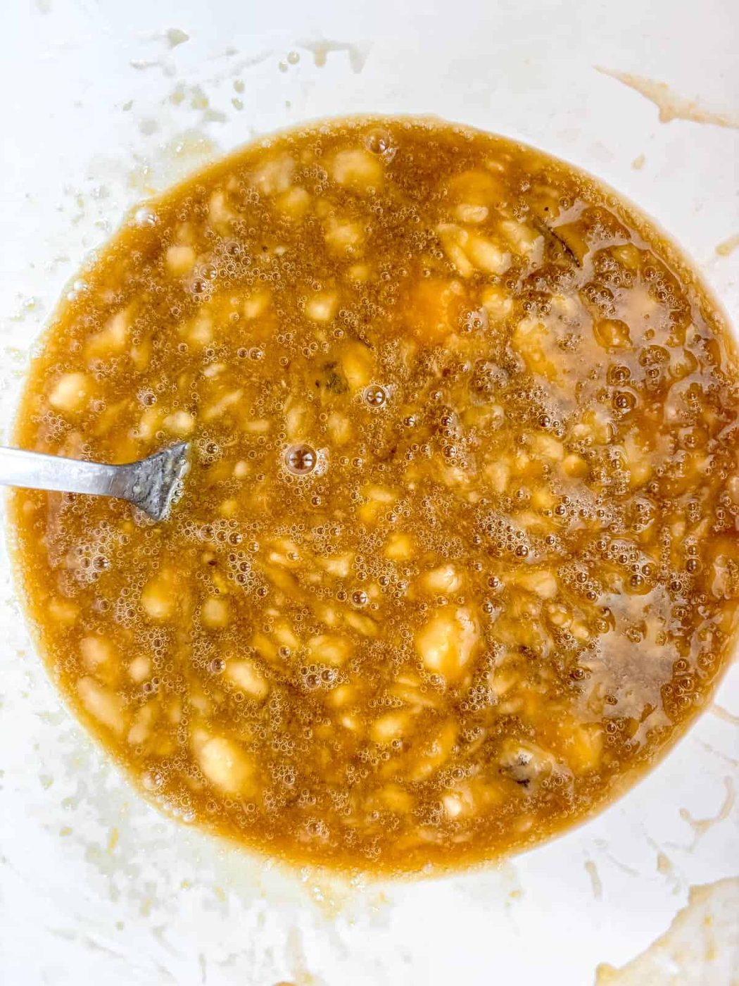 Wet ingredients for maple banana bread mixed together in a bowl.