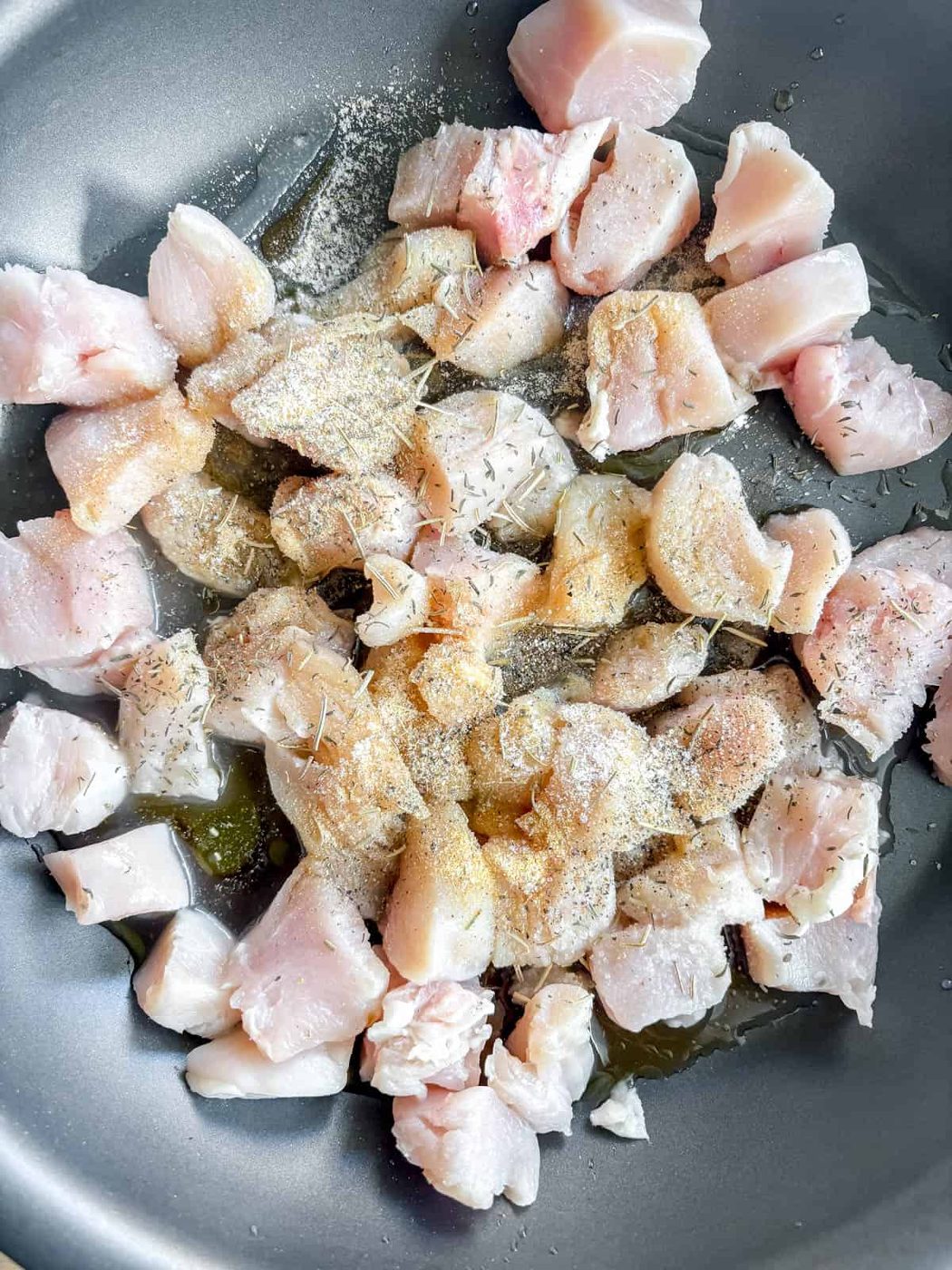 Chicken, lemon, maple syrup and herbs in a pan.