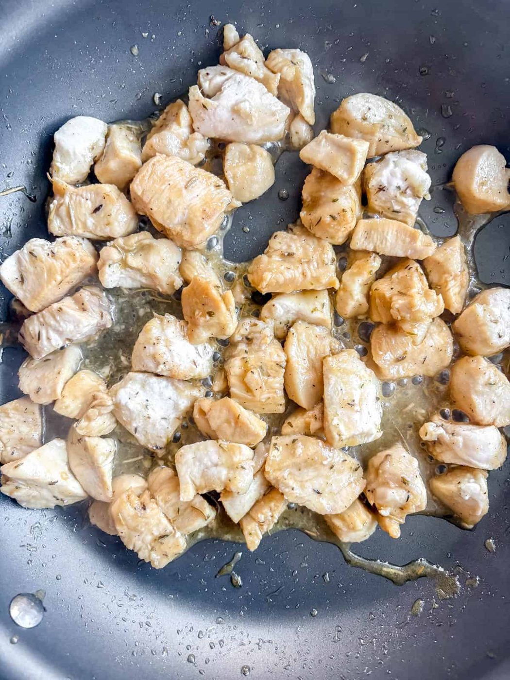Chicken, lemon, maple syrup and herbs in a pan cooking.