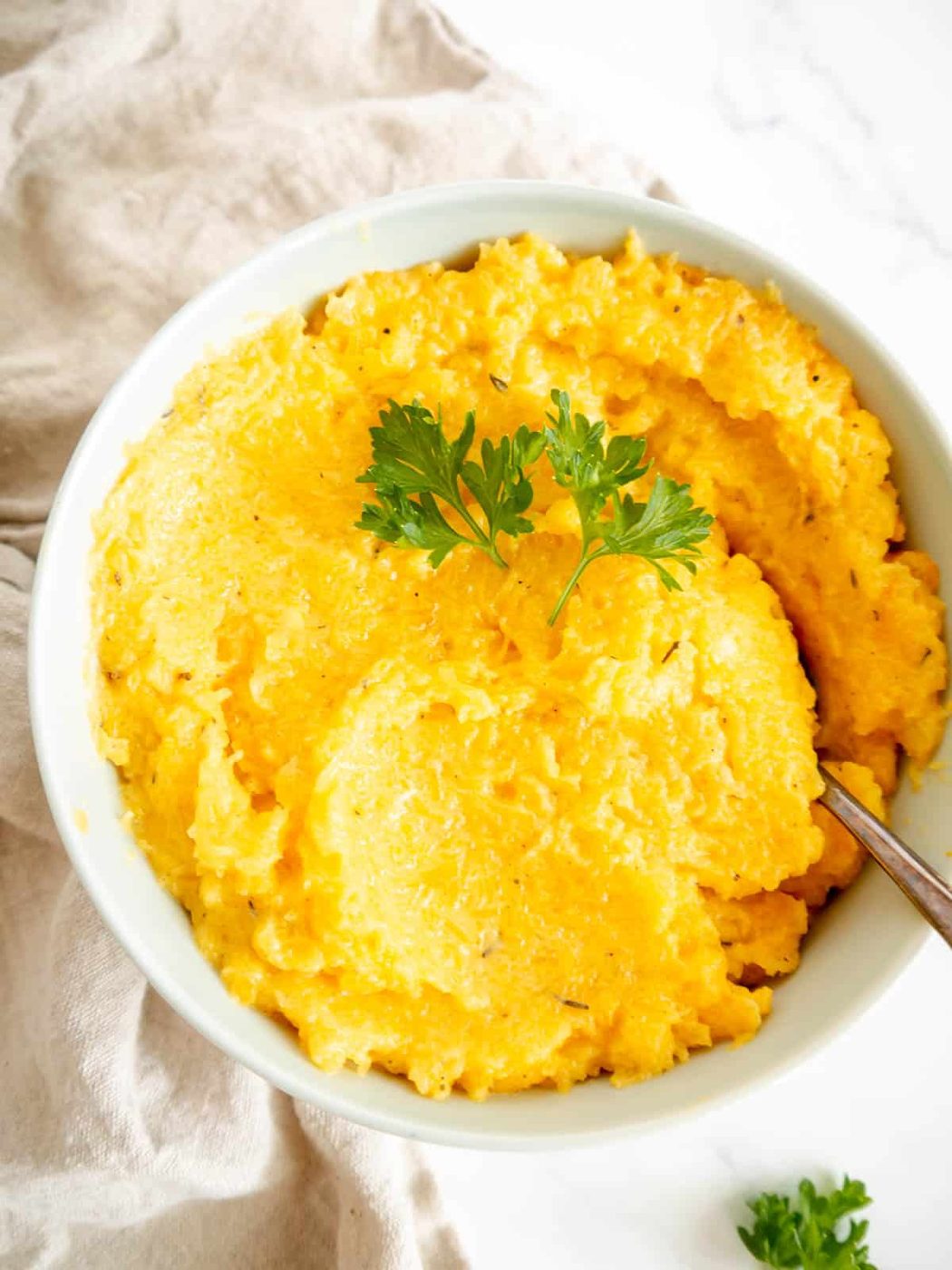 Butternut squash mash in a bowl with a spoon.