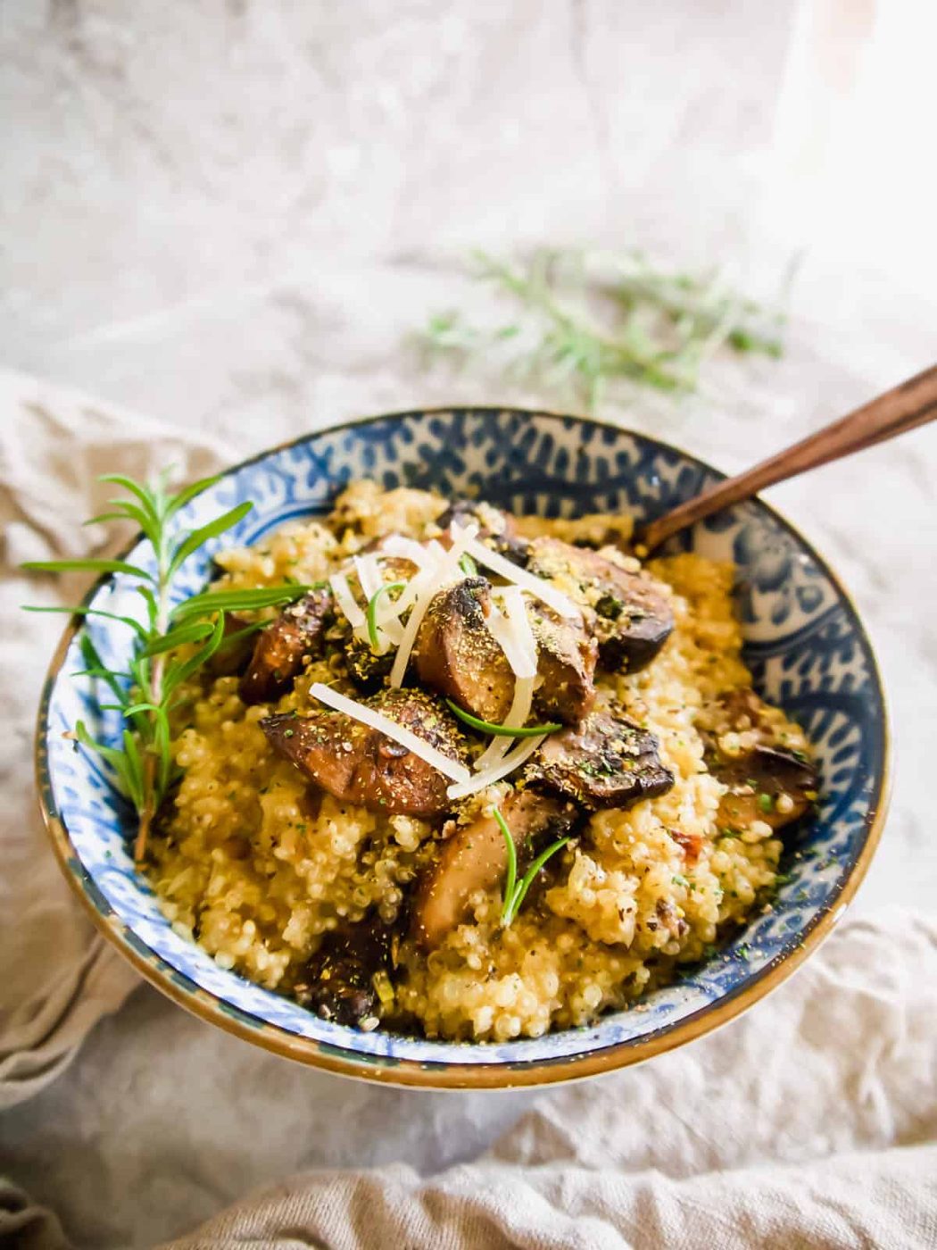 Quinoa mushroom risotto in a bowl with a spoon in it.