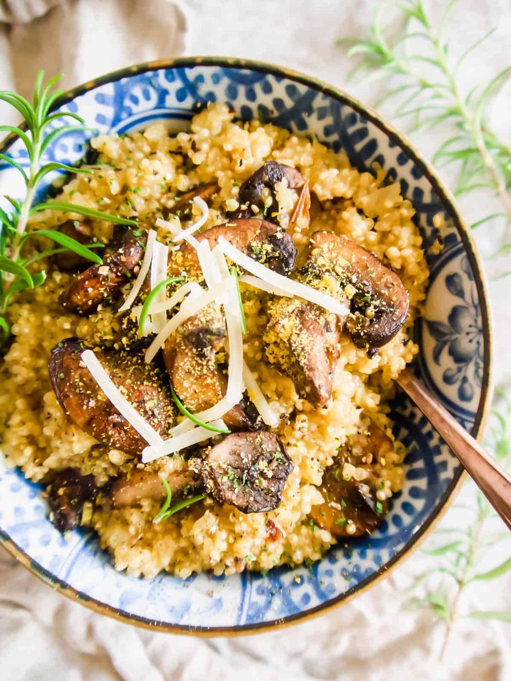 Aerial view of creamy quinoa risotto in a bowl with mushrooms and Parmesan on top.