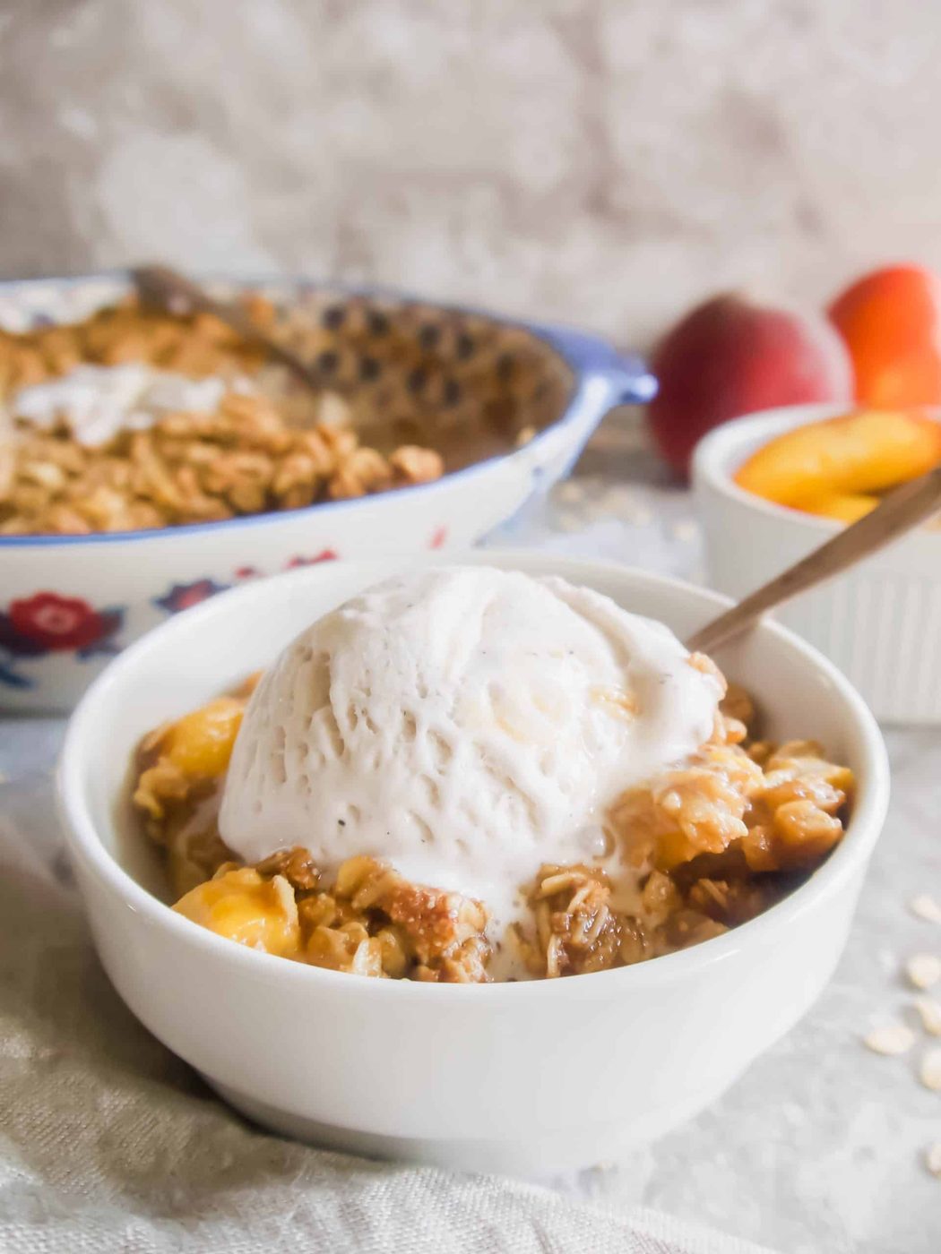 Stone fruit crisp in a bowl with ice-cream on top.