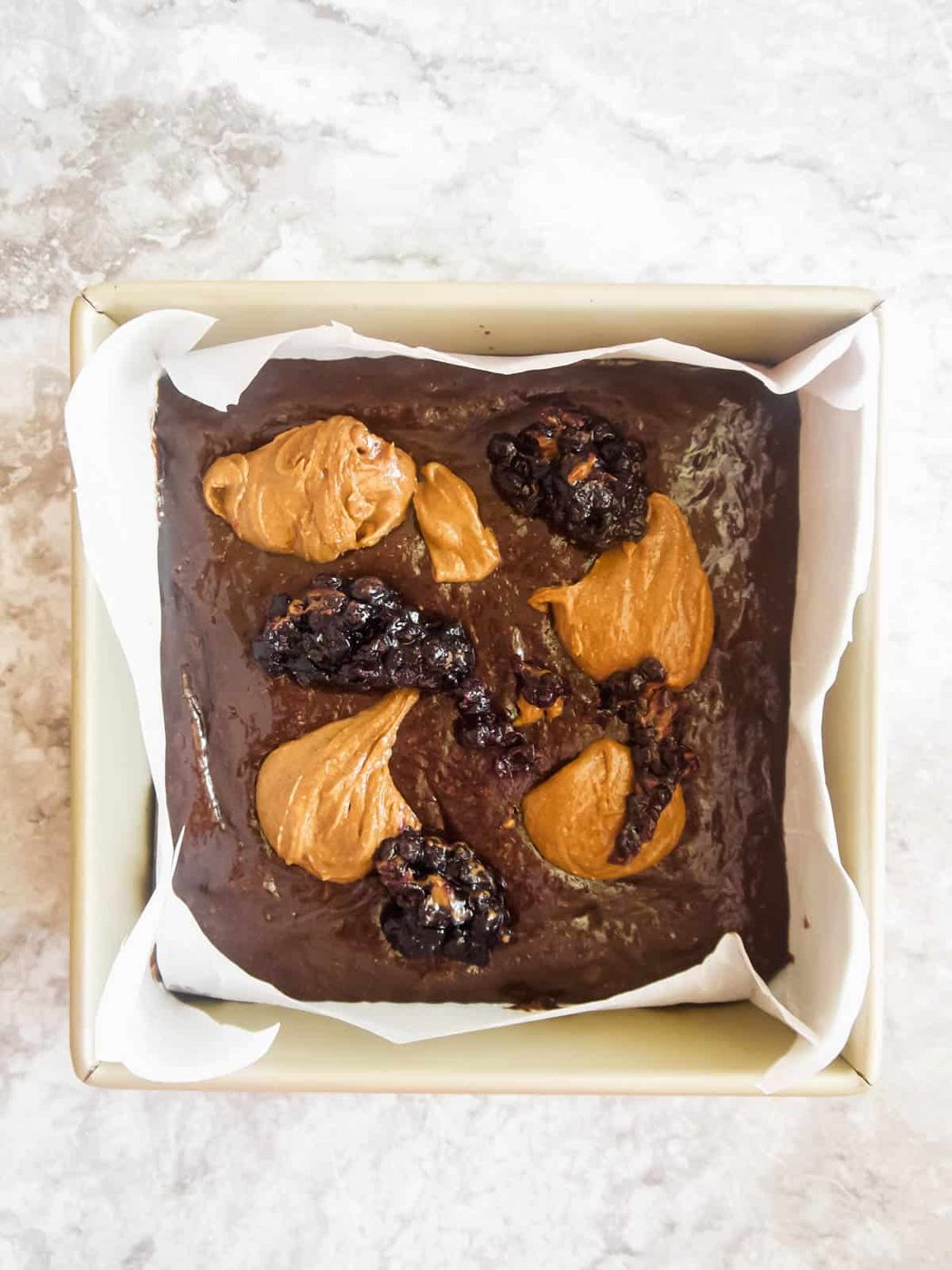 Almond butter and jelly dollops on top of brownie batter.