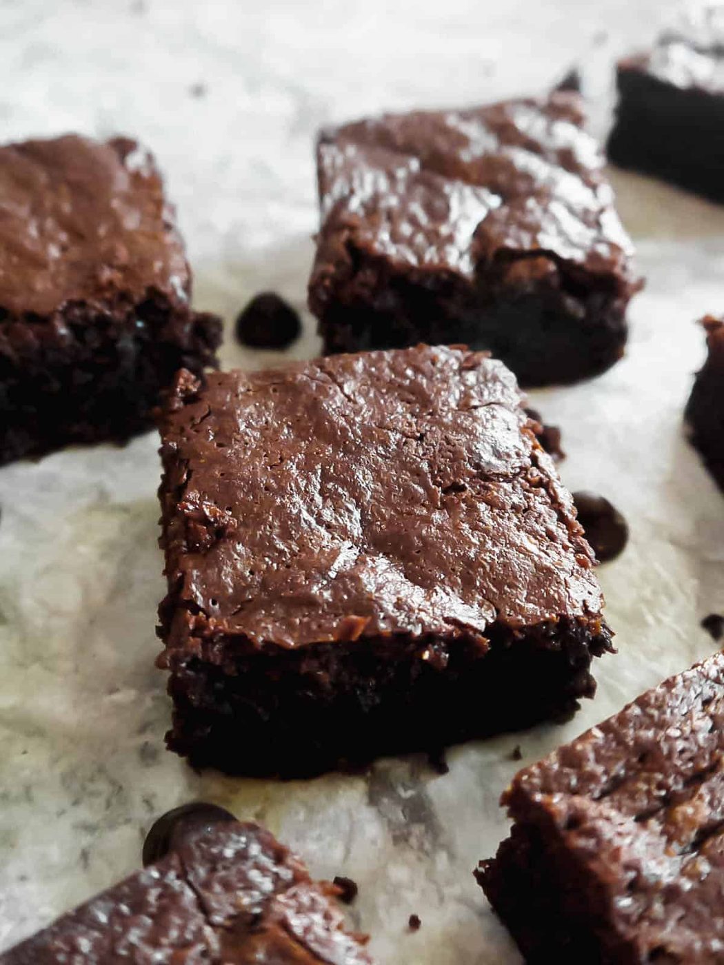 Slices of olive oil brownies with chocolate chips next to them.