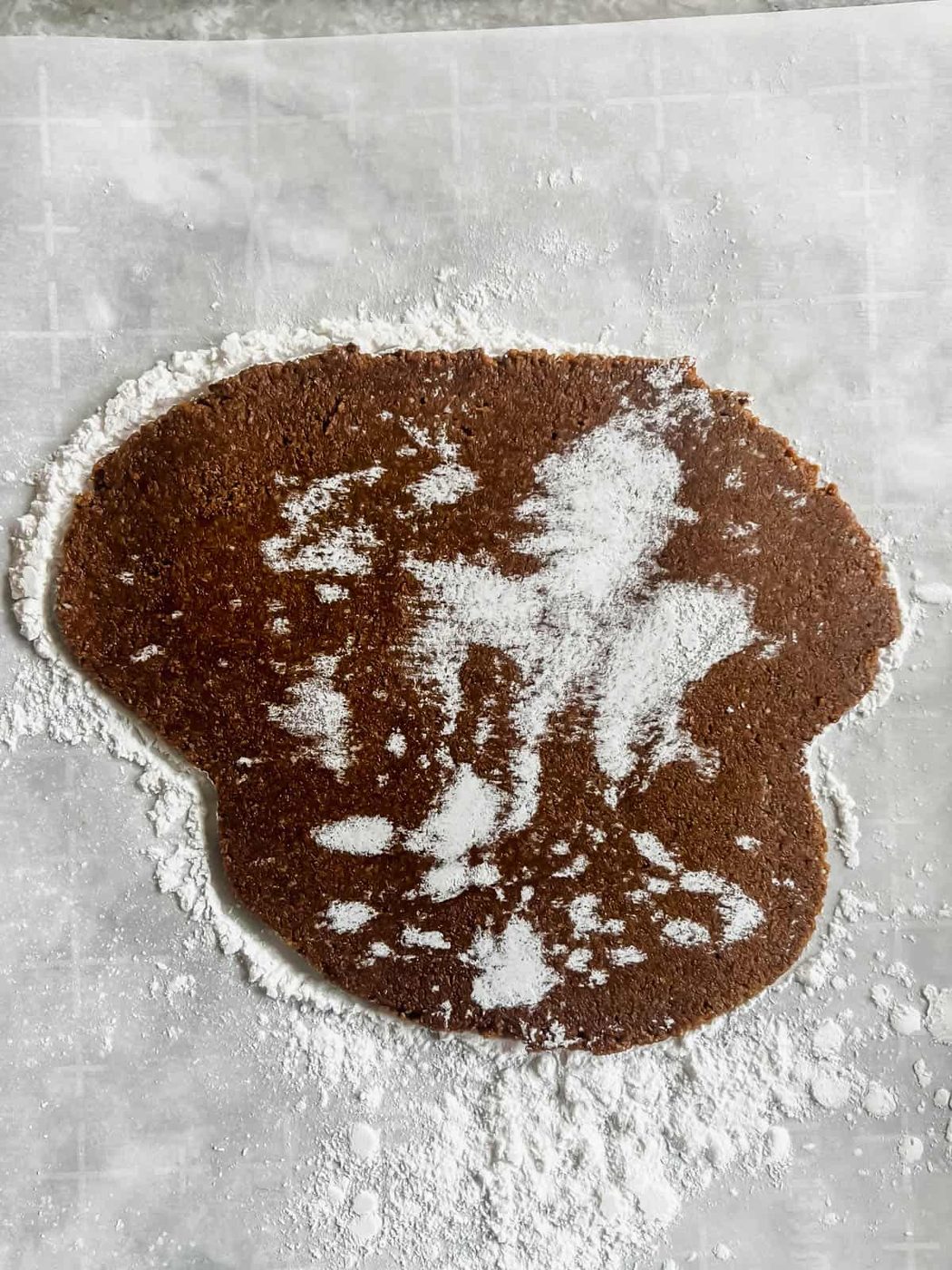 Rolled out gingerbread dough on parchment paper.