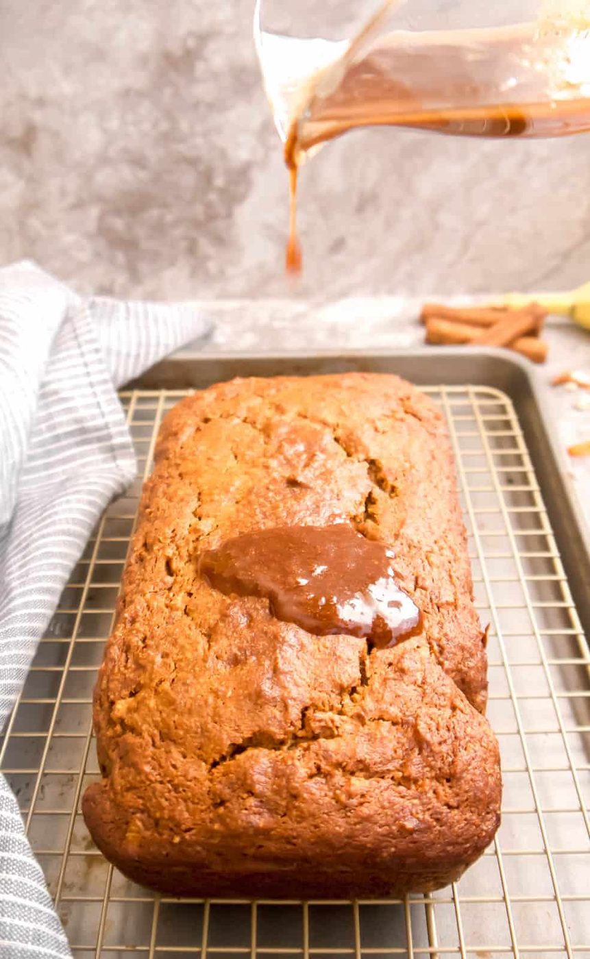 Pouring the cinnamon maple coconut oil frosting drizzle on top of the banana bread.