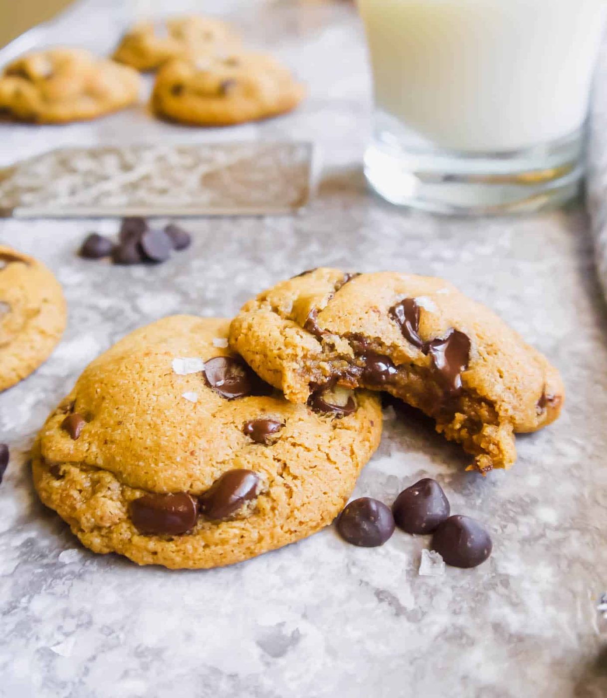 One almond flour chocolate chip Cookie with a bite taken out on top of another cookie.