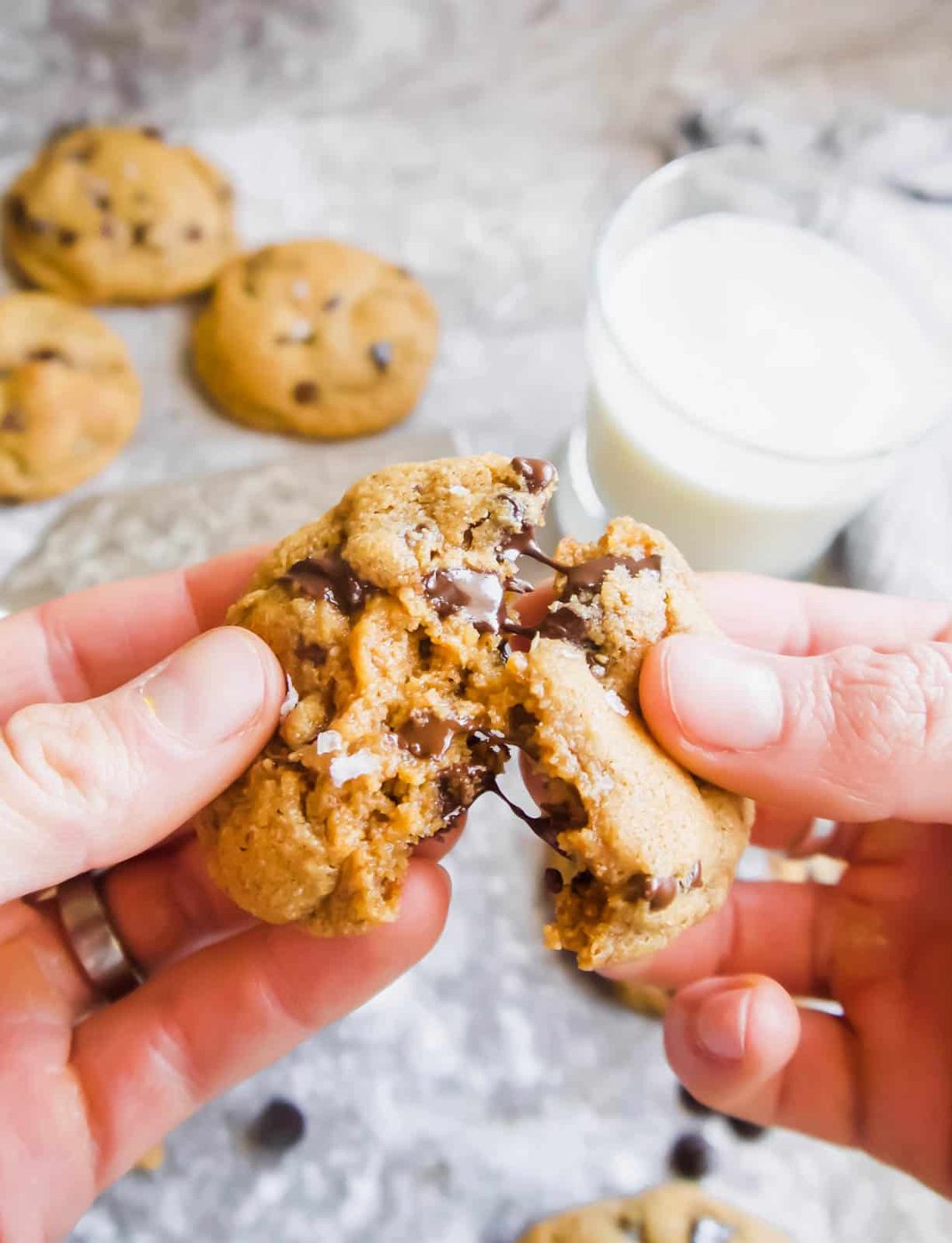 Coconut oil chocolate chip cookies broken in half in hands.