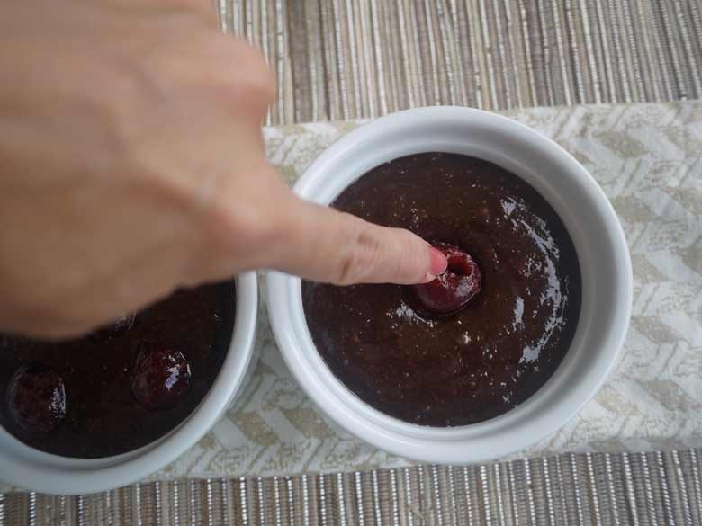Cherries being added to ramekins.