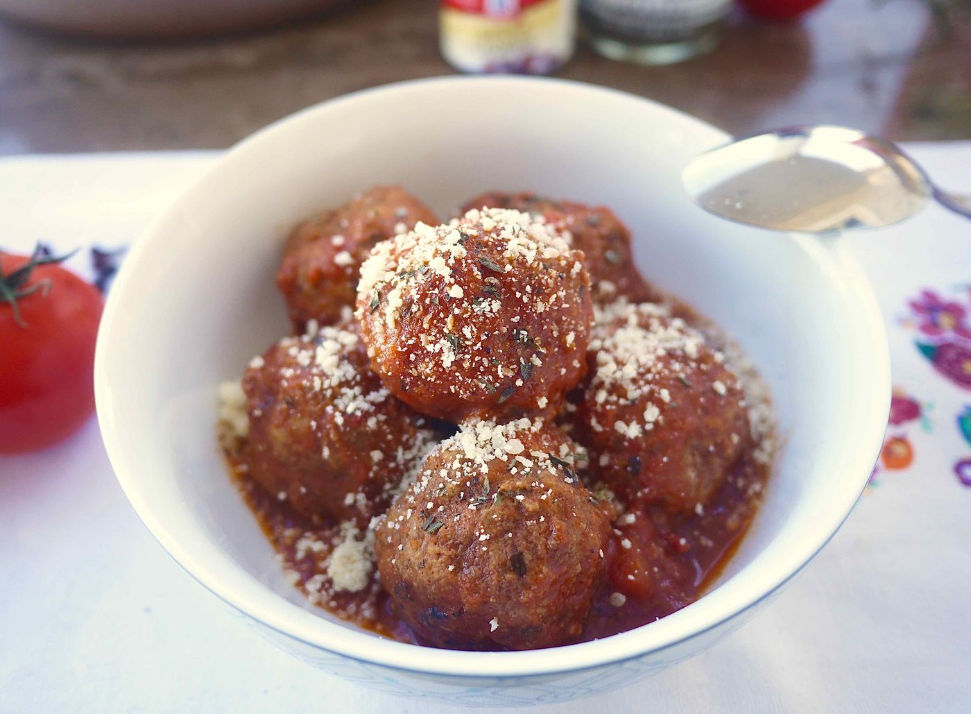 Almond flour meatballs and sauce in a bowl with Parmesan on top.