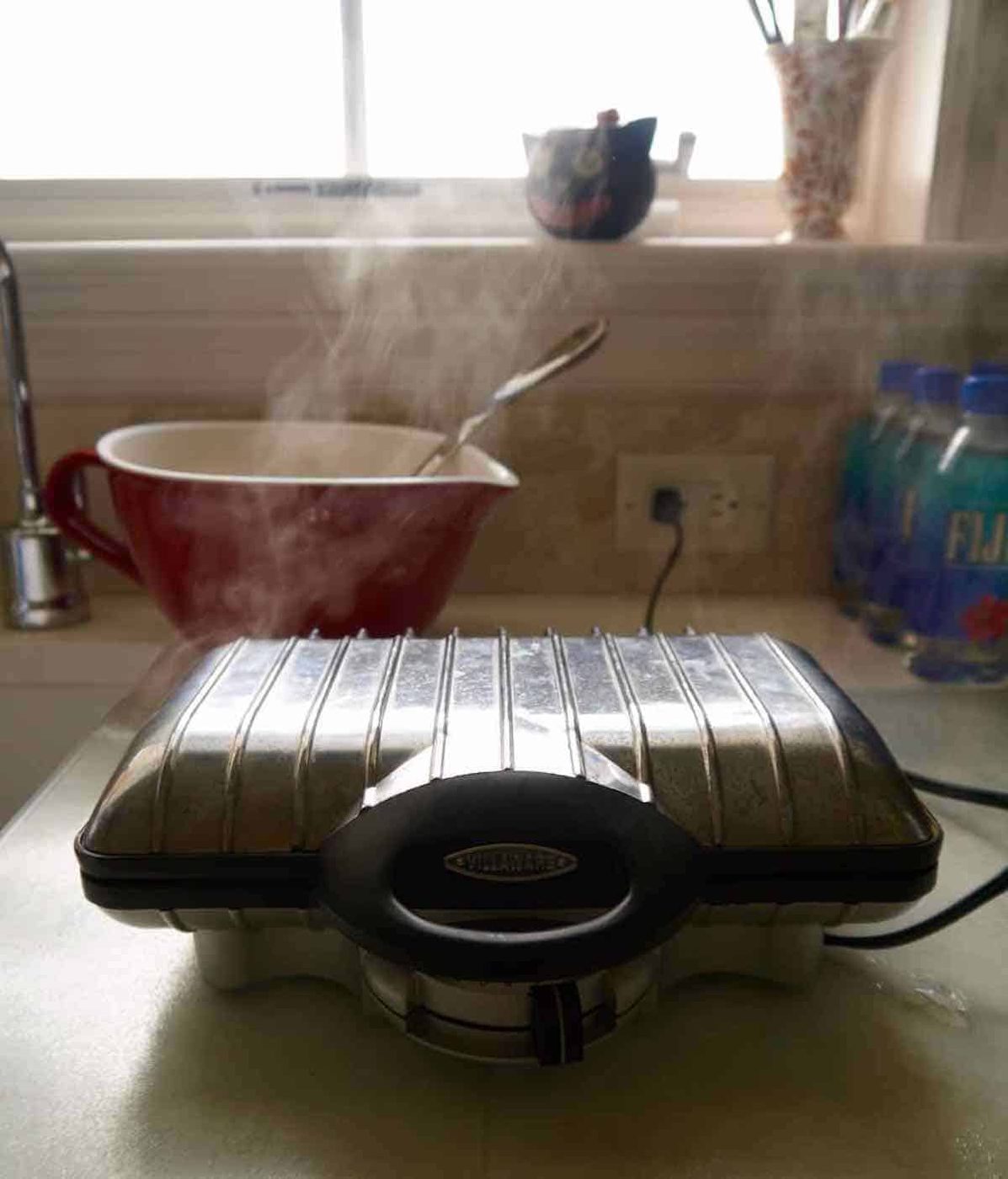 Waffle maker cooking paleo pumpkin waffles.