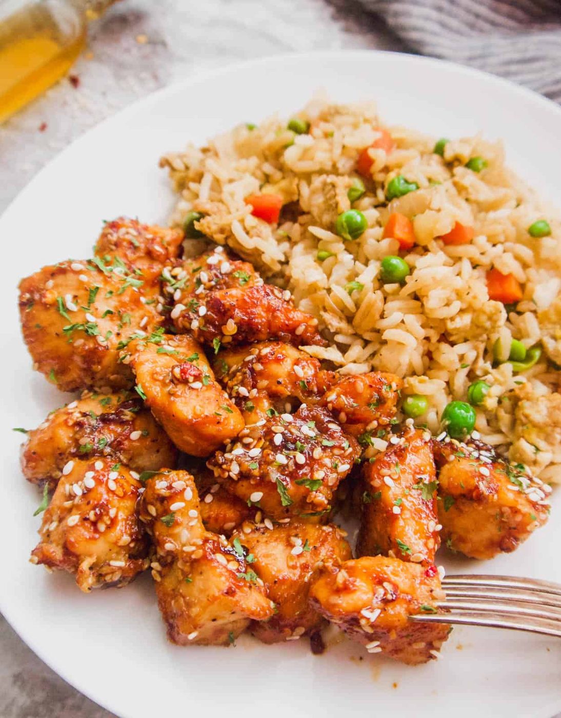 Paleo sesame chicken next to fried rice on a plate.