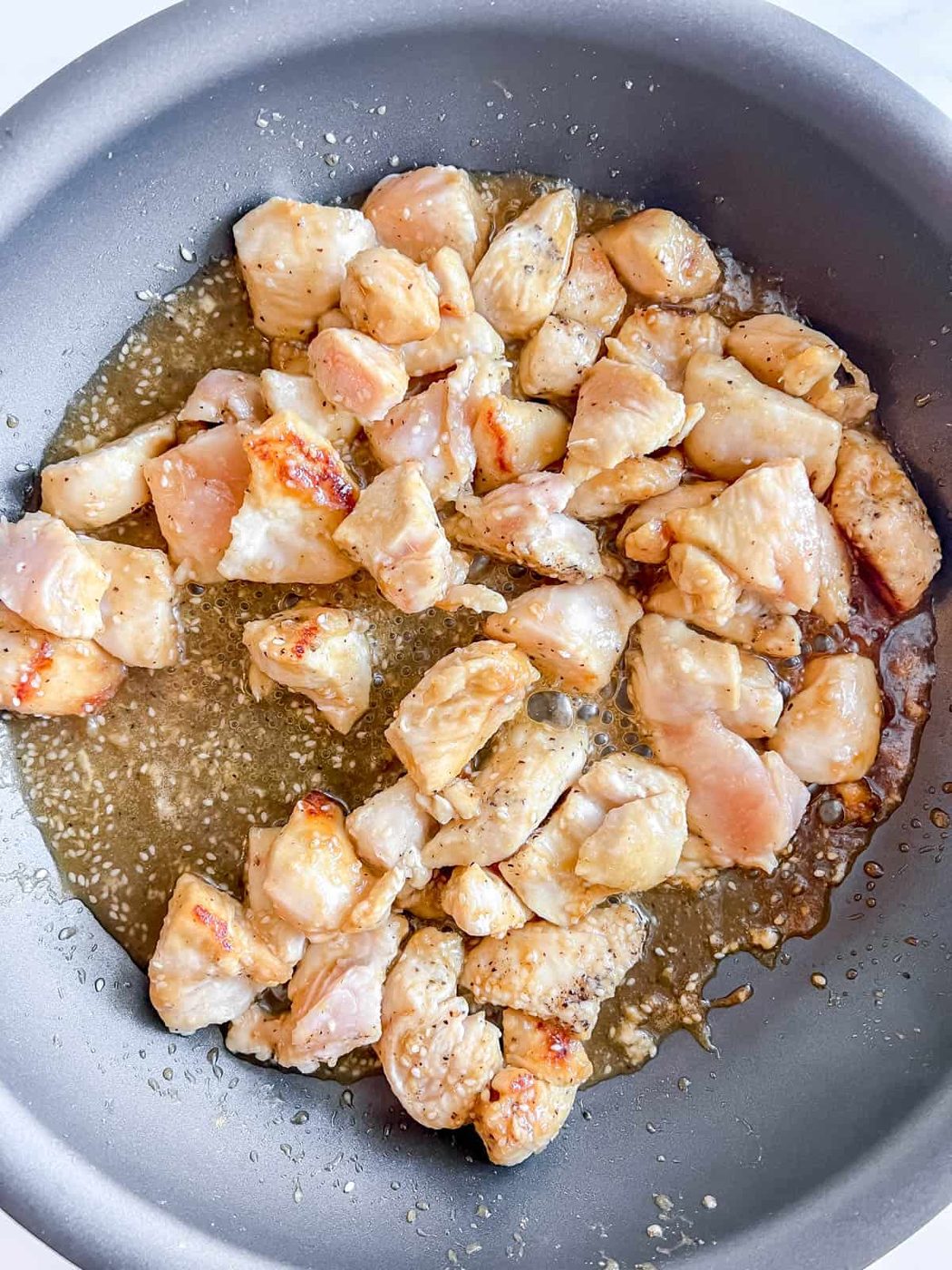 The chicken cooking in the pan.