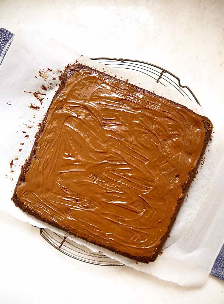 Melted chocolate on top of the coconut brownies.