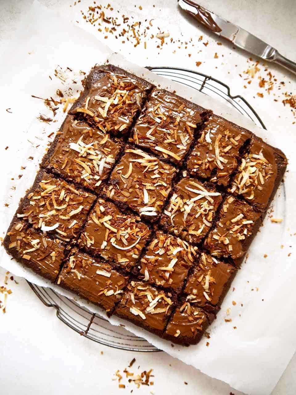 Sliced coconut brownies on a cooling rack.