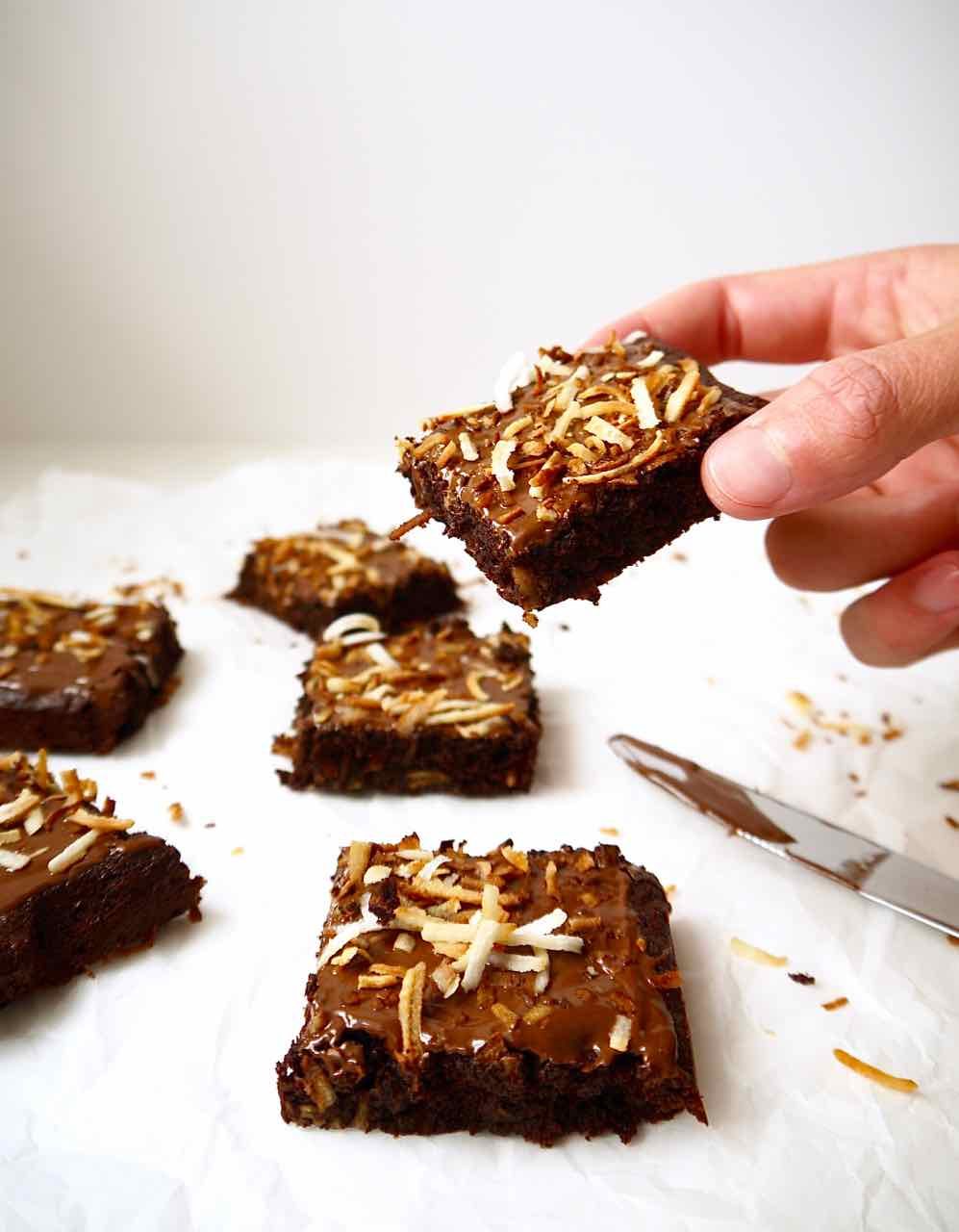 A hand picking up a coconut chocolate brownie.