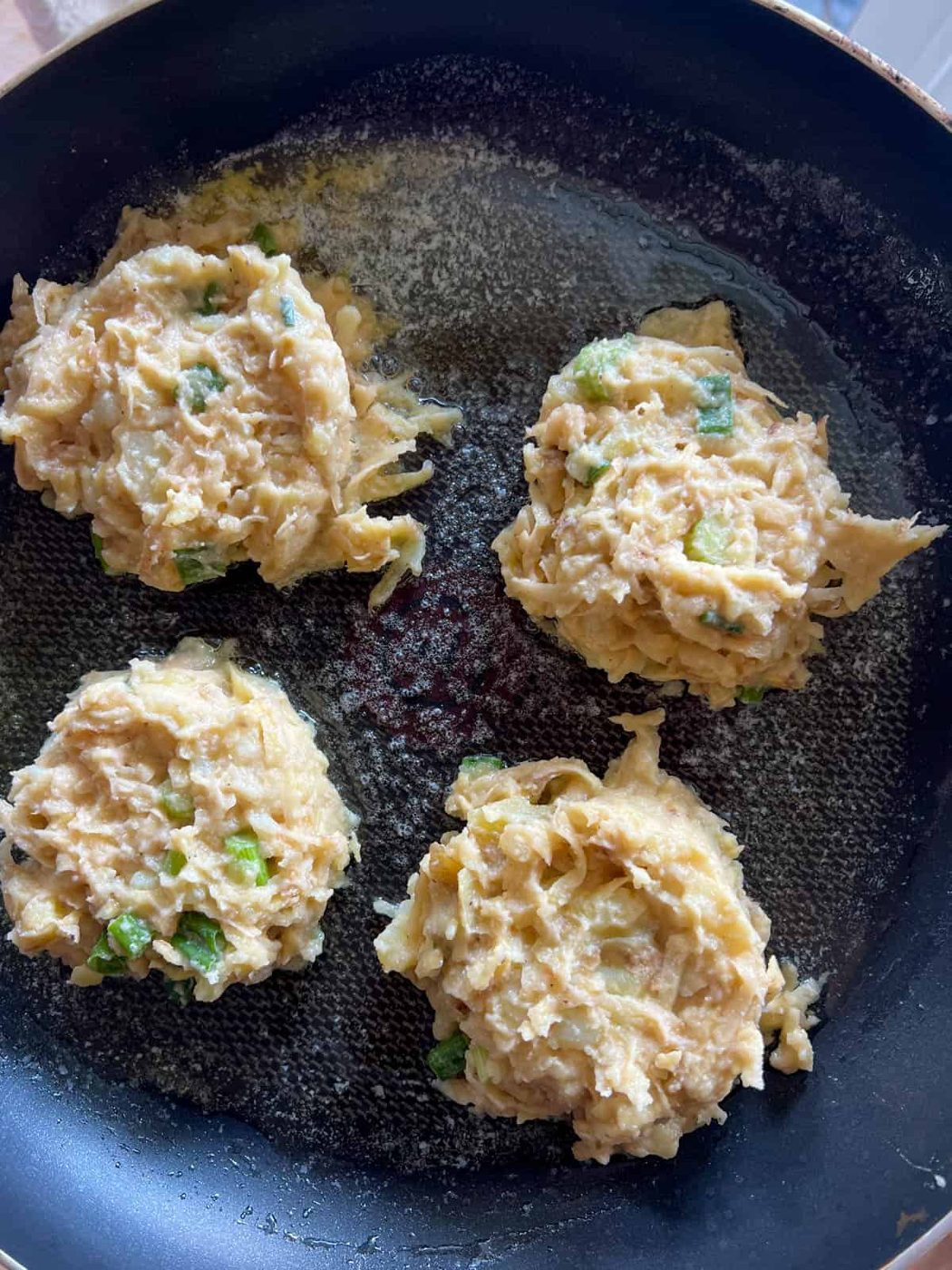 The potato pancake batter on a frying pan.
