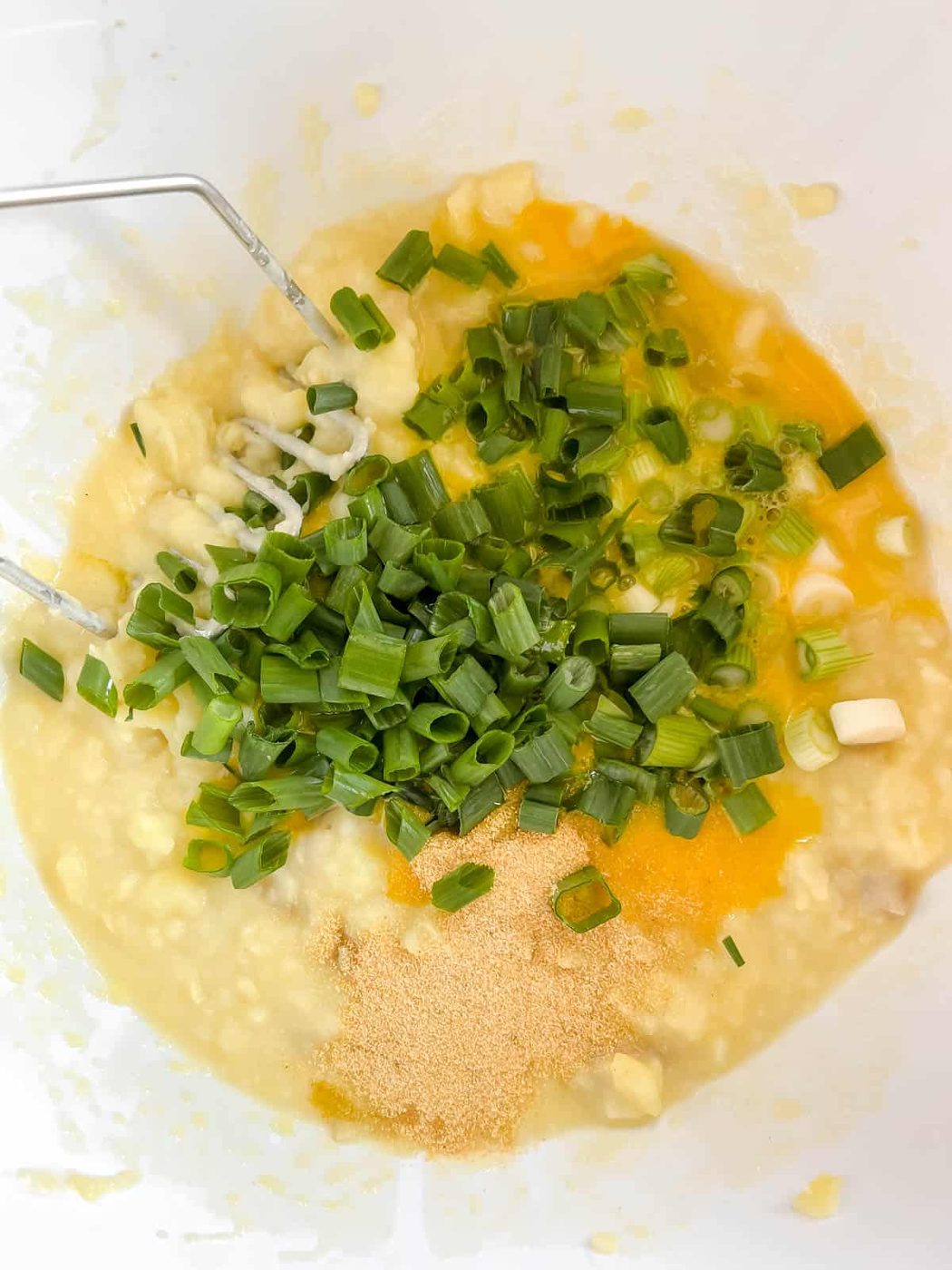 Adding pencil onions, eggs, and garlic to the mashed potatoes.
