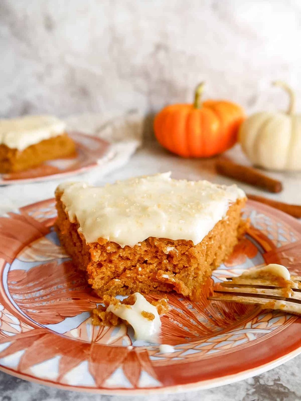 A bite taken out of a slice of lighter pumpkin cake on a plate.