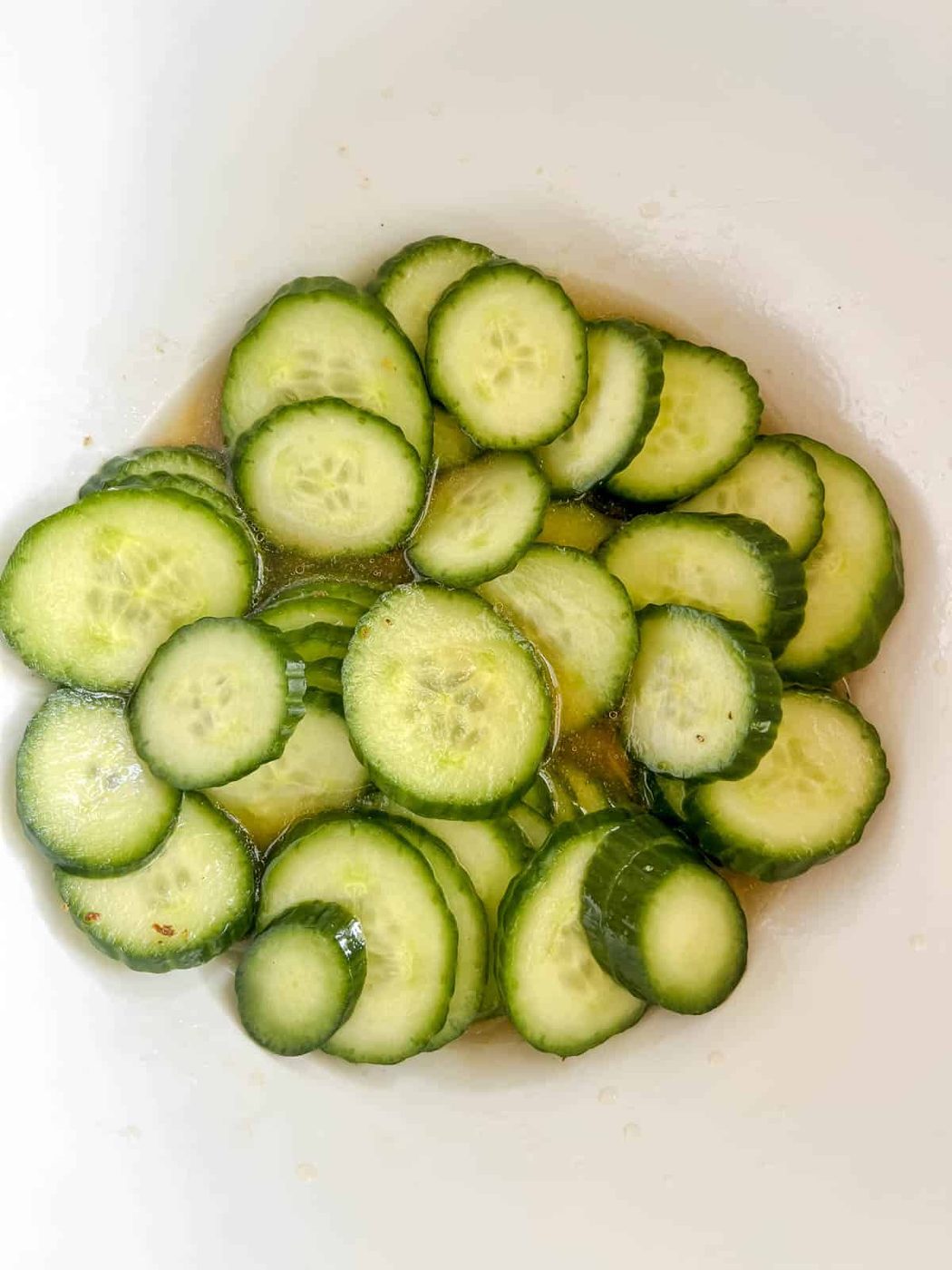 Vinegar added to sliced cucumbers.