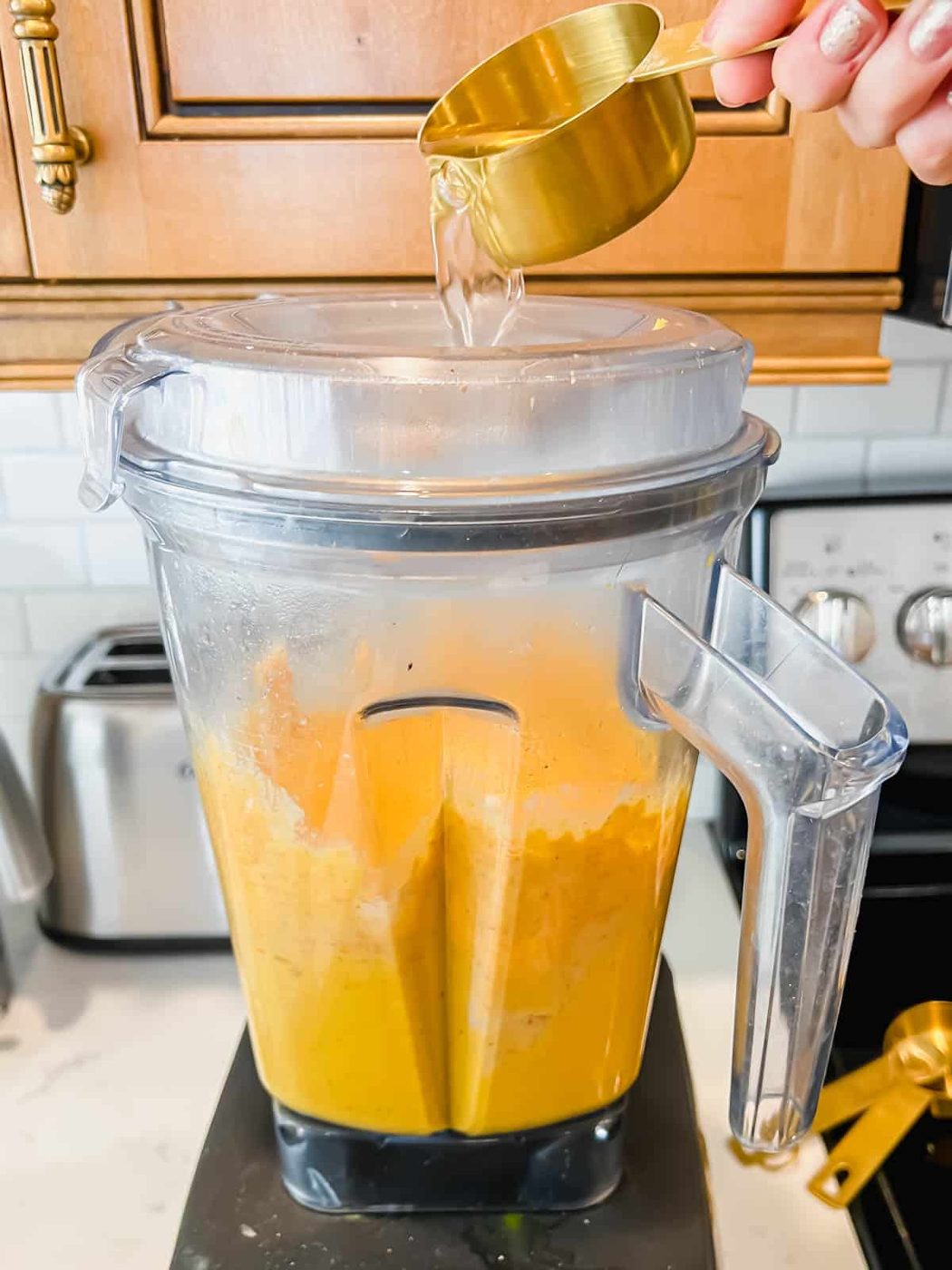 Water being poured into the blender while the hummus is mixing.