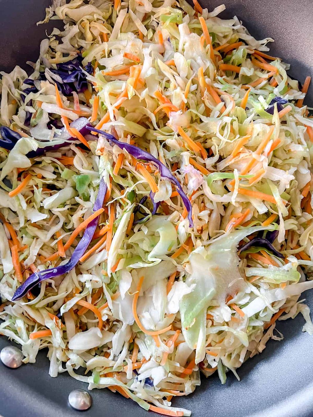 Sautéing cabbage and carrots in a pan.