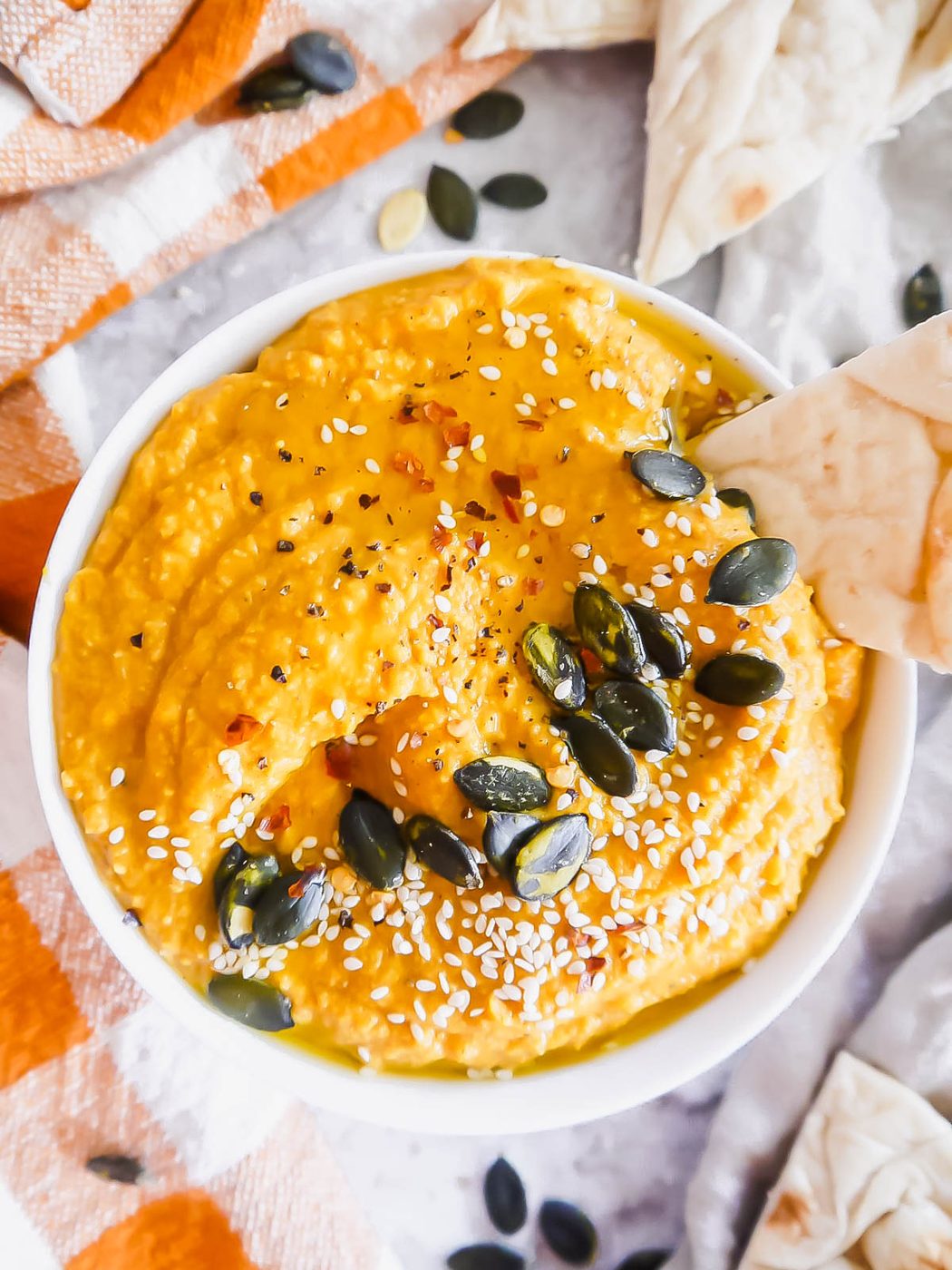 Piece of pita inside savory pumpkin dip.