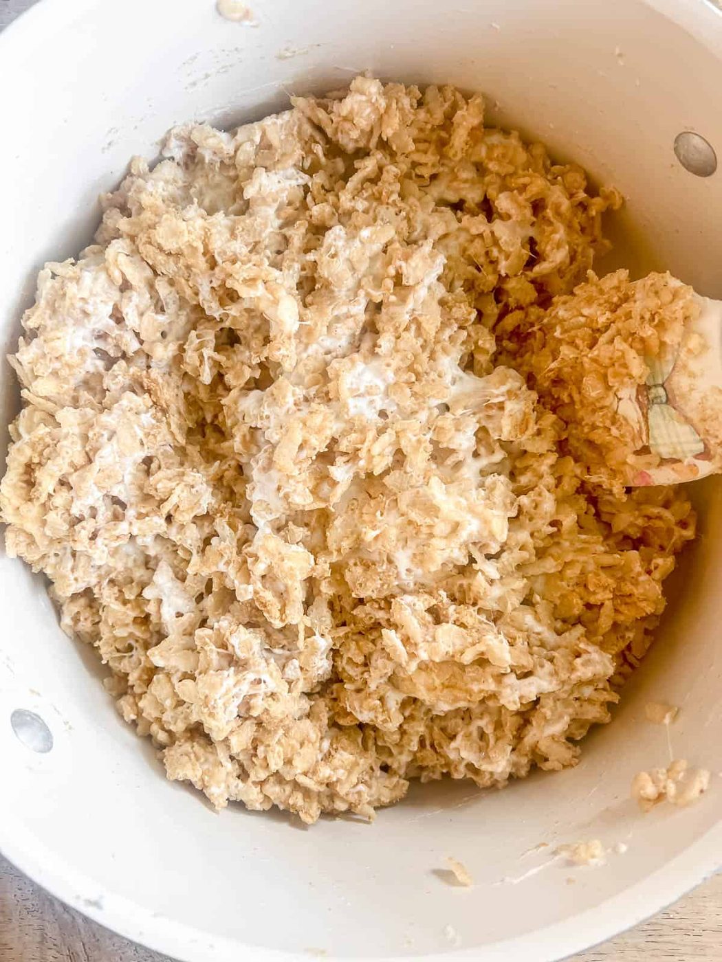 Graham crackers and crispy rice cereal mixed into melted marshmallows in a pan.