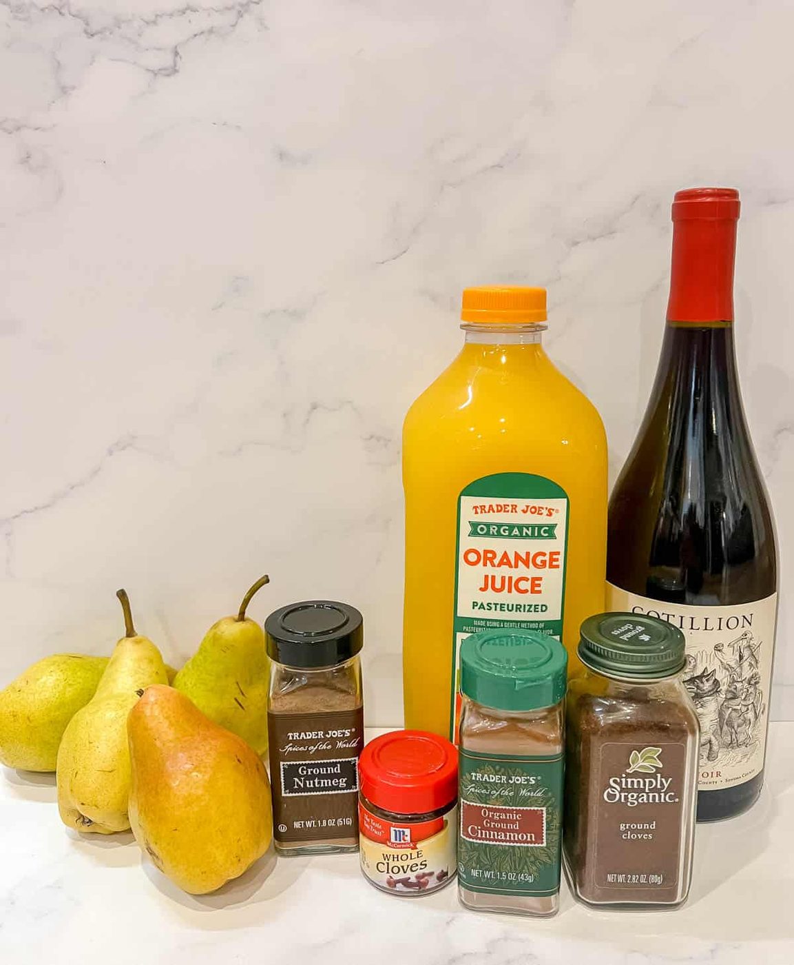Ingredients needed to make spiced poached pears in orange juice and red wine.
