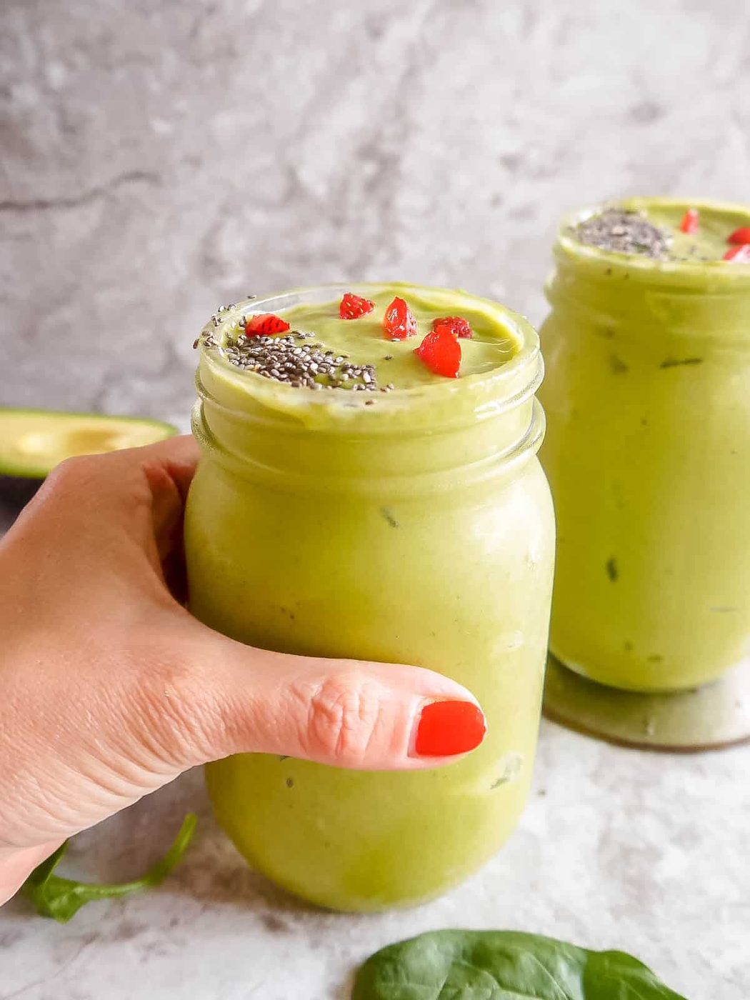 Smoothie with spinach banana and strawberries in two cups.