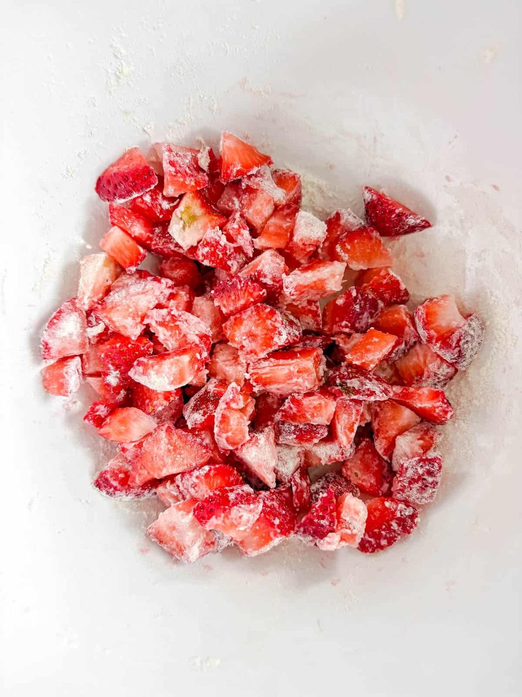 Chopped strawberries in a bowl with flour on top.