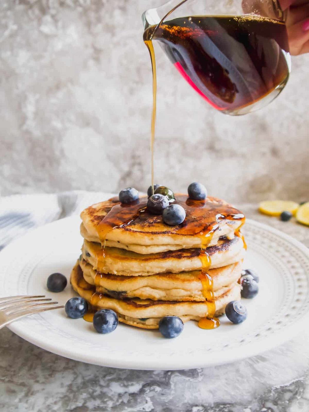 Maple syrup is poured on paleo blueberry pancakes.