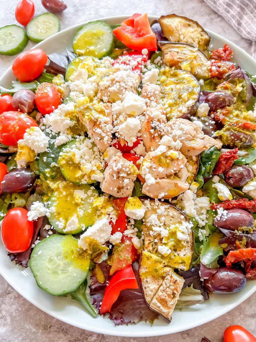 Finished greek salad with grilled chicken on a plate.