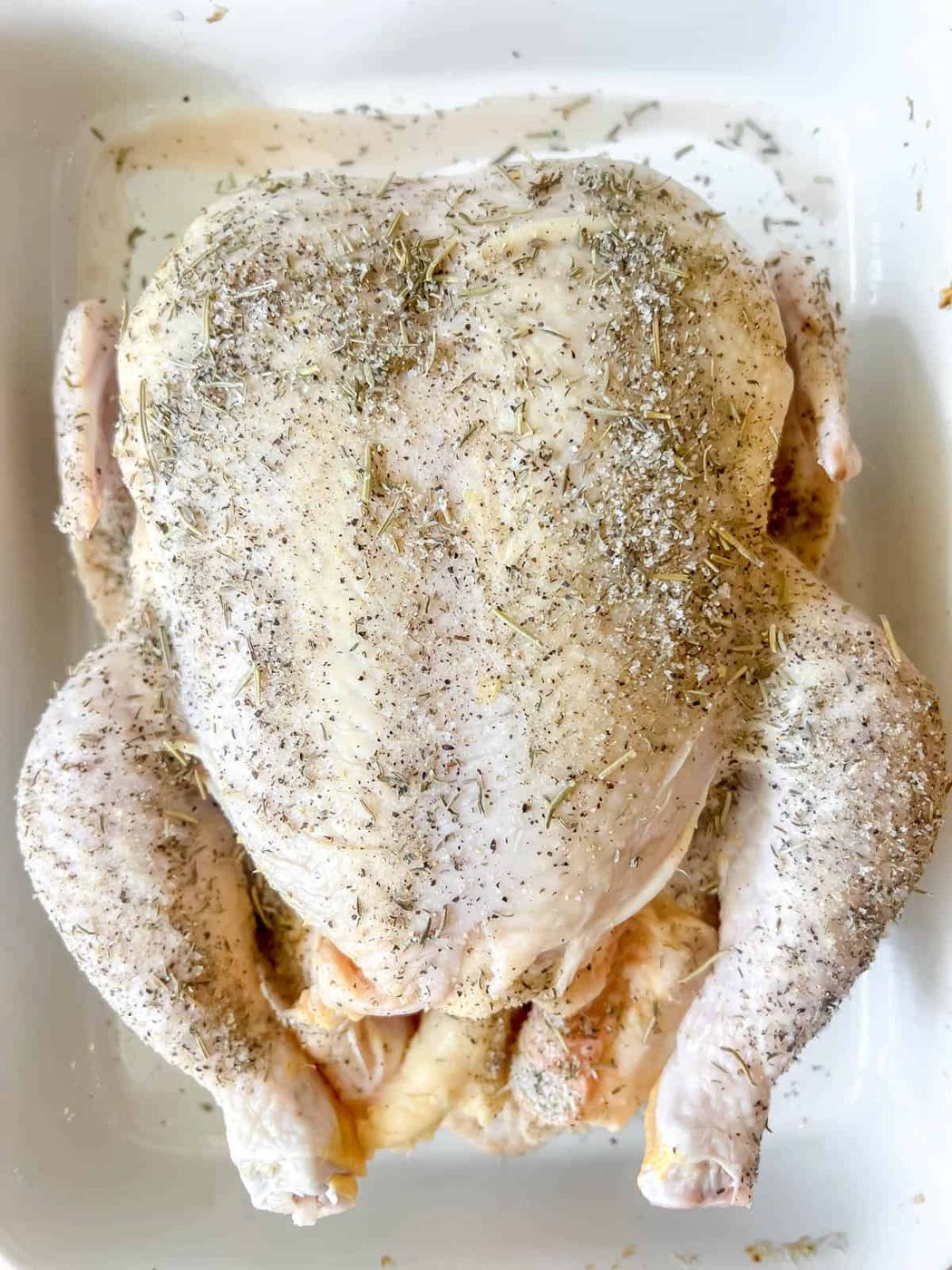 Herbs on top of raw chicken.