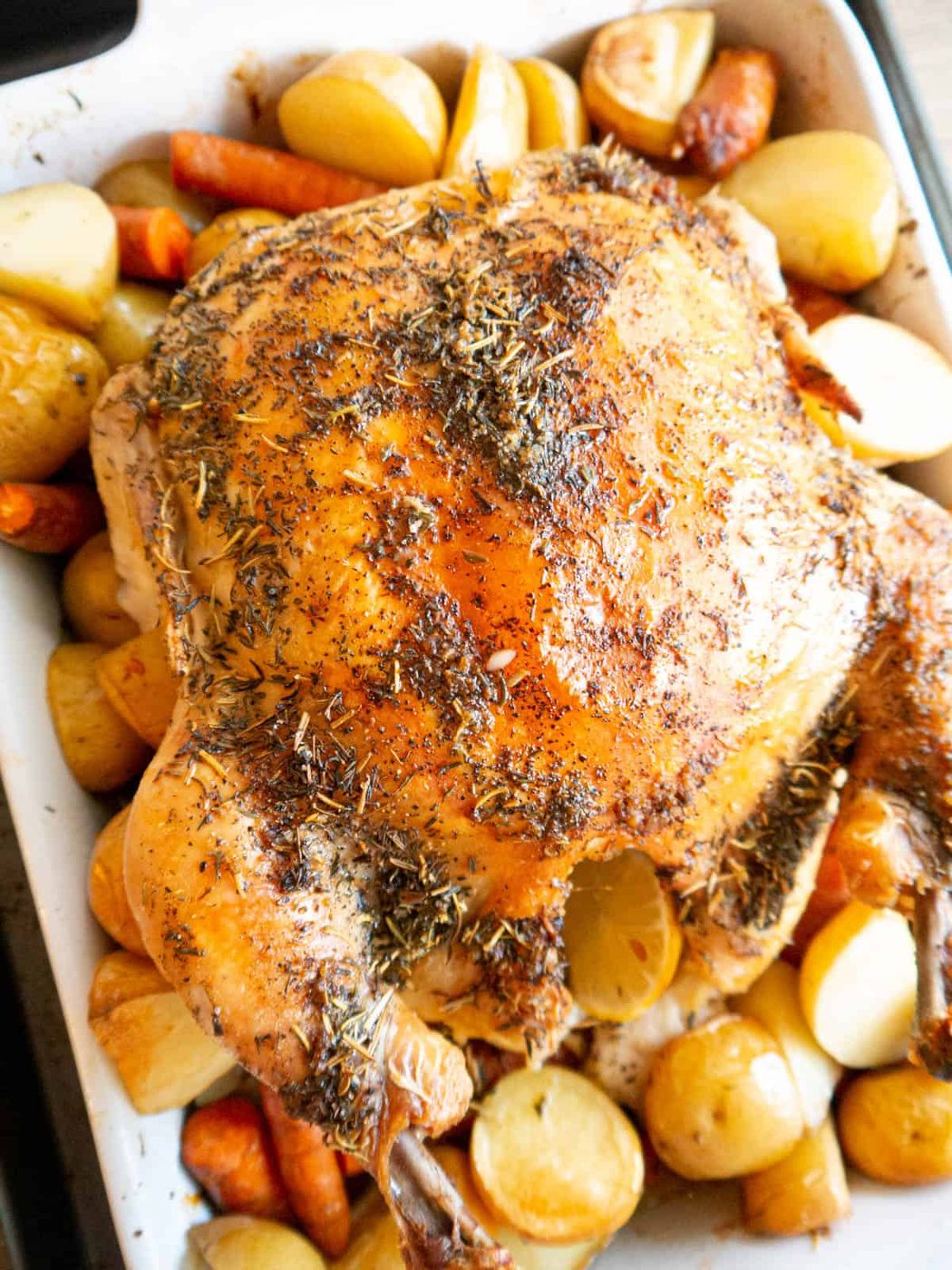 Roast lemon thyme chicken with root vegetables in a pan.