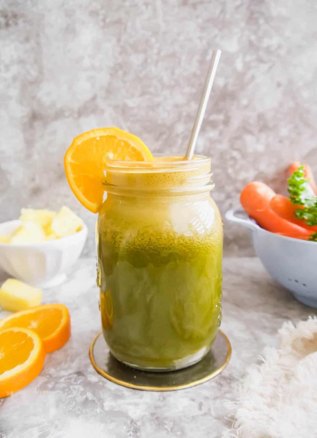 Kale carrot juice in a mason jar with a straw.