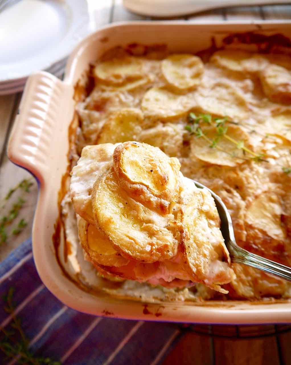 Spoon scooping out scalloped potatoes.