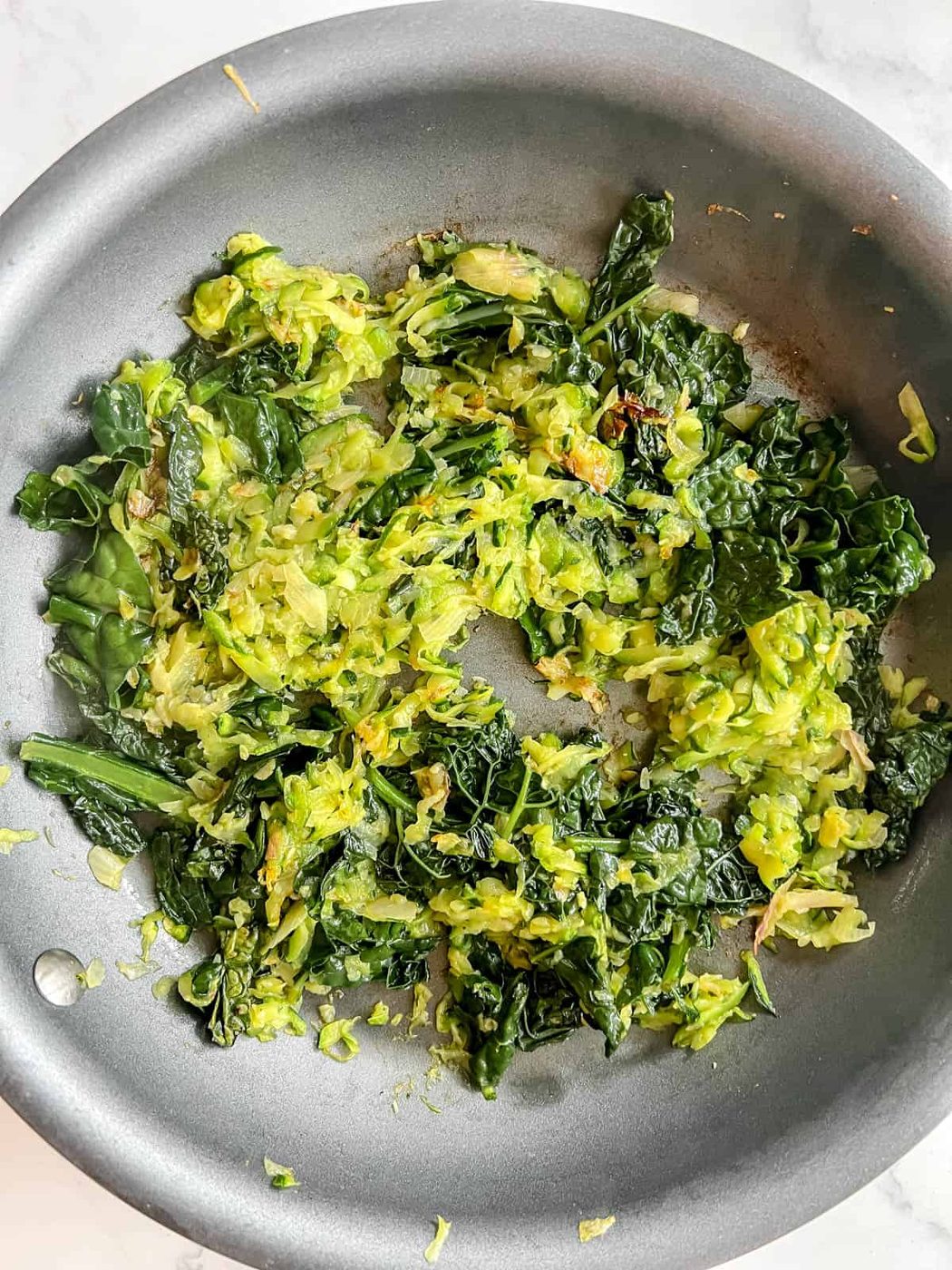 Cooked kale and zucchini in a pan.