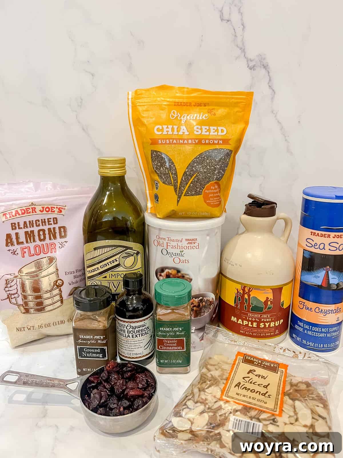 Artisan Olive Oil Granola Almonds and Chia 3 An overhead shot showcasing all the essential raw ingredients for olive oil granola, including rolled oats, sliced almonds, chia seeds, maple syrup, and spices, arranged on a rustic surface.