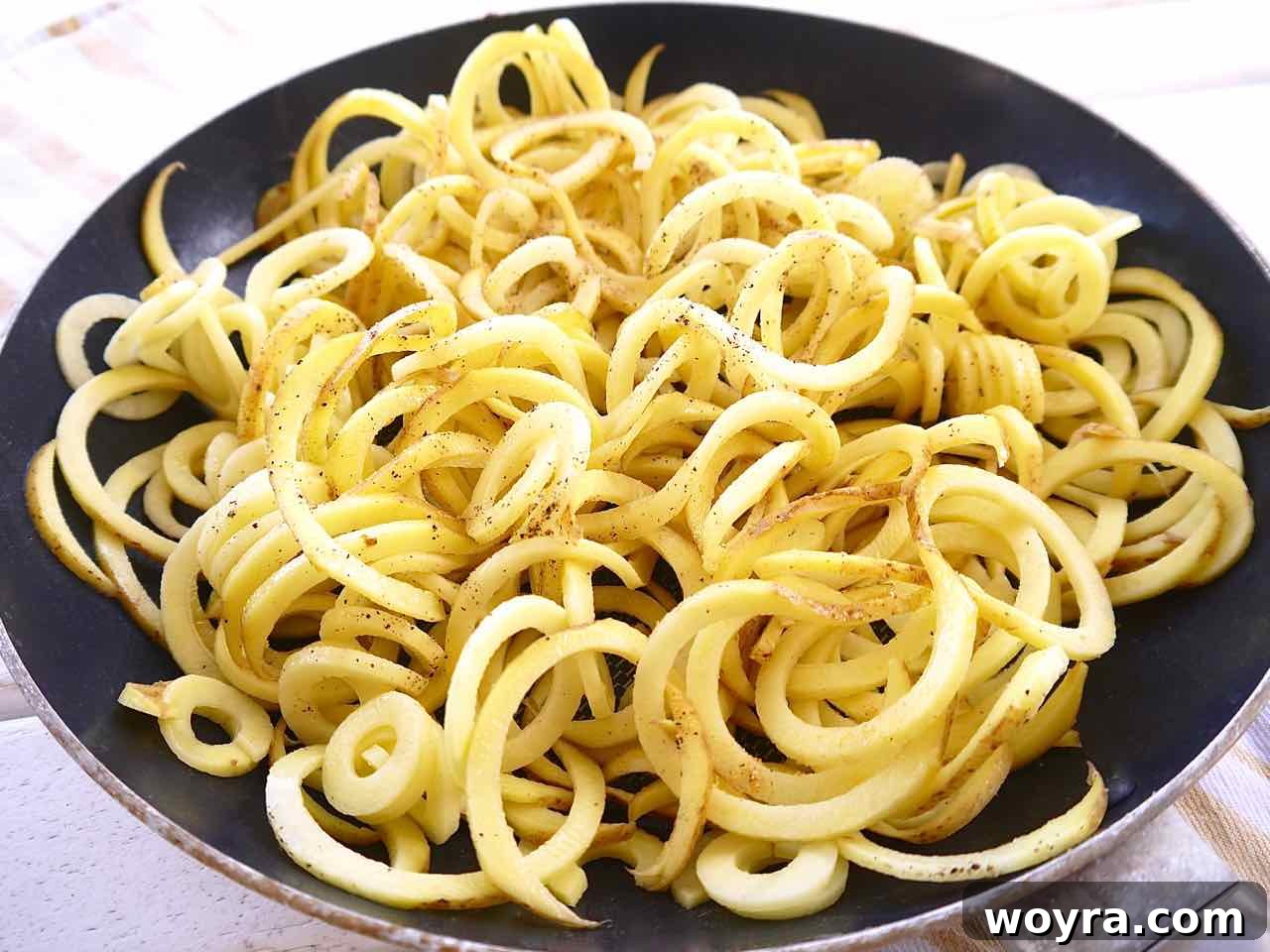 Wholesome Chicken, Mushroom and Spiral Potato Bake 4 Freshly spiralized potatoes tossed with olive oil and seasonings in a frying pan, ready for baking.