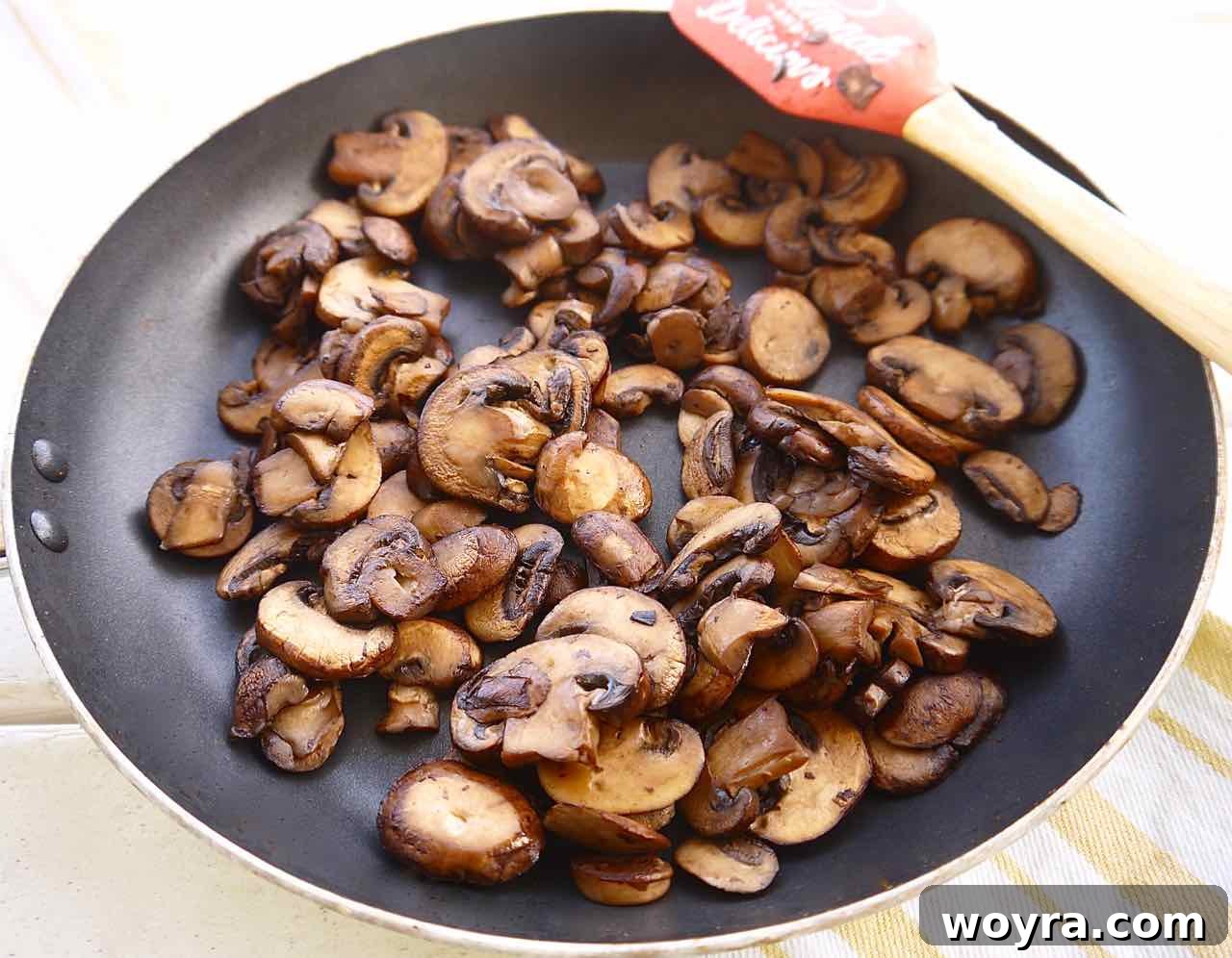 Wholesome Chicken, Mushroom and Spiral Potato Bake 5 Sliced baby bella mushrooms achieving a rich golden-brown color in a hot pan, essential for deep umami flavor.