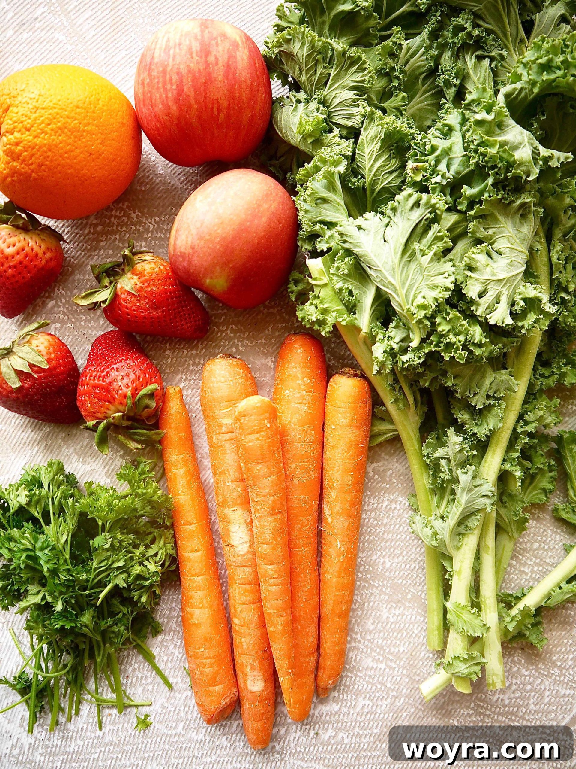 Root to Leaf Radiance 3 Fresh organic parsley, kale, carrots, apples, strawberries, and oranges laid out on a wooden cutting board, ready for juicing.