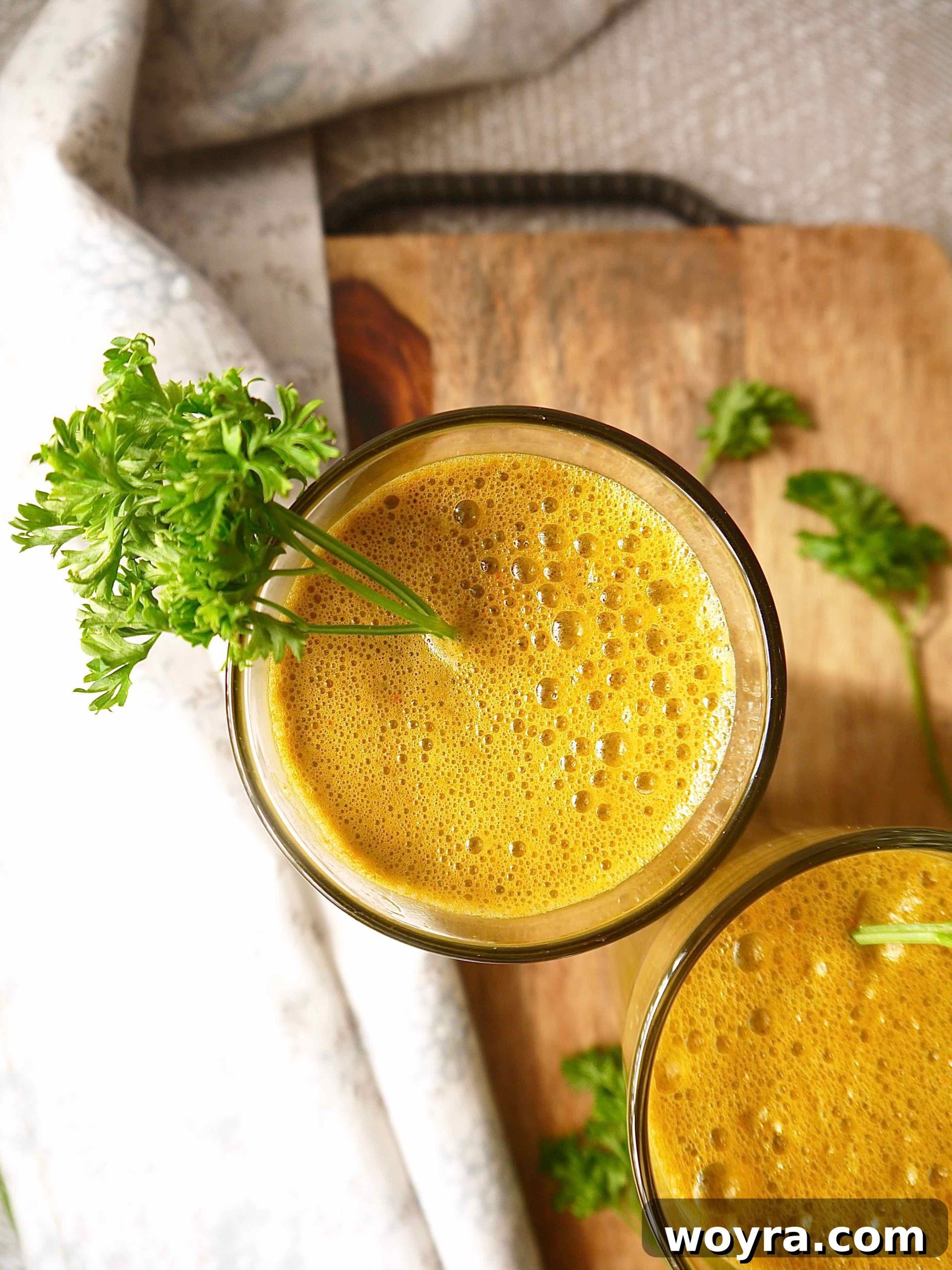Root to Leaf Radiance 4 Close-up of a glass of Carrot Kale Apple Juice with a fresh sprig of parsley and a kale leaf, highlighting its vibrant green color and freshness.