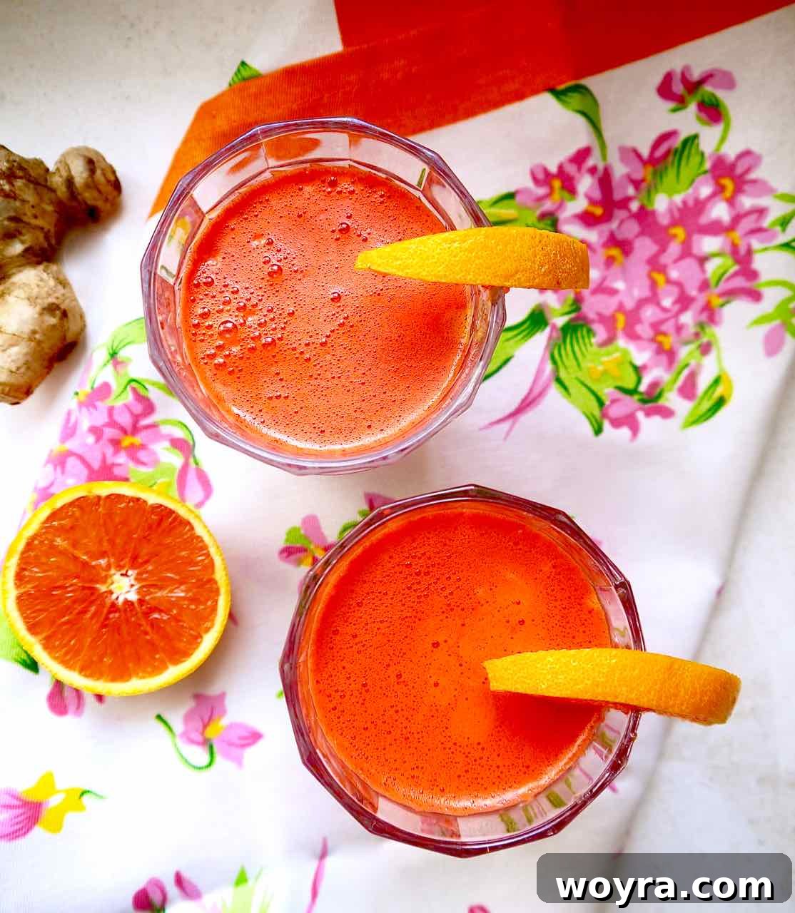 Vibrant Harvest Elixir 5 Apple Carrot Beet Ginger Juice in two cups with oranges on the rims.